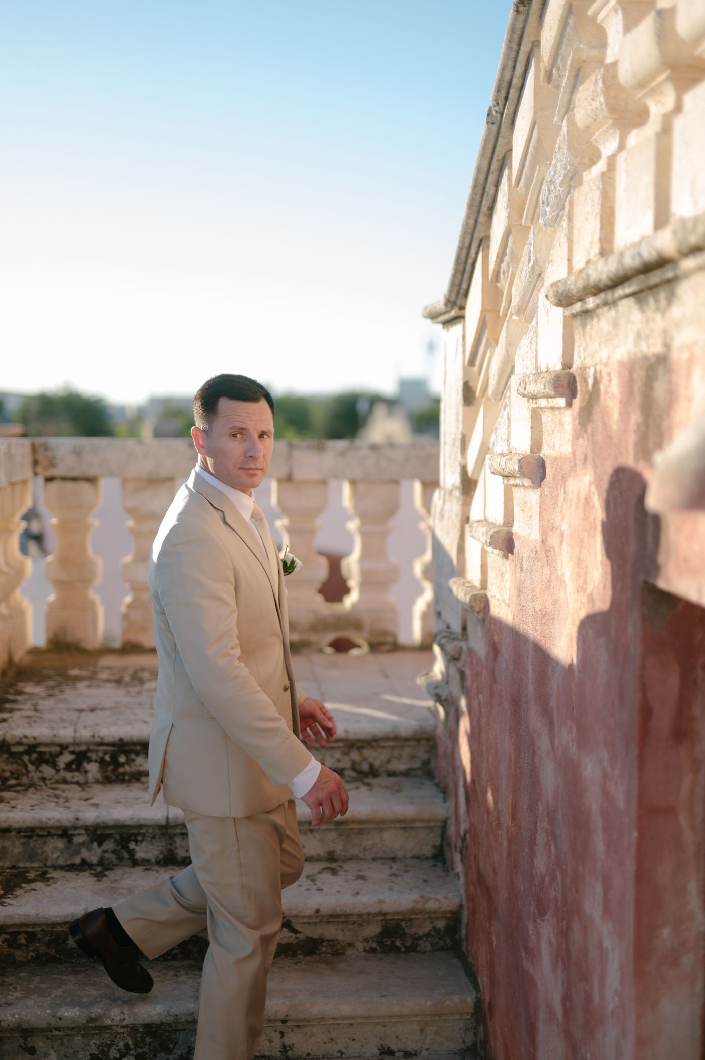 A person in a light colored suit poses on a rustic balcony in warm sunlight, creating a series of candid moments.