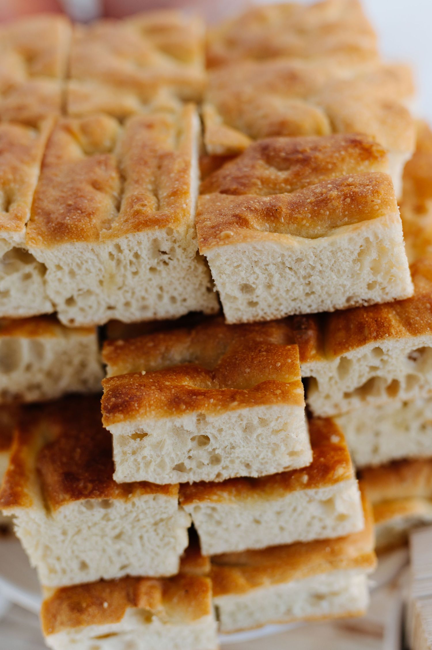 Stacked pieces of homemade focaccia bread showing its airy texture and golden brown crust.