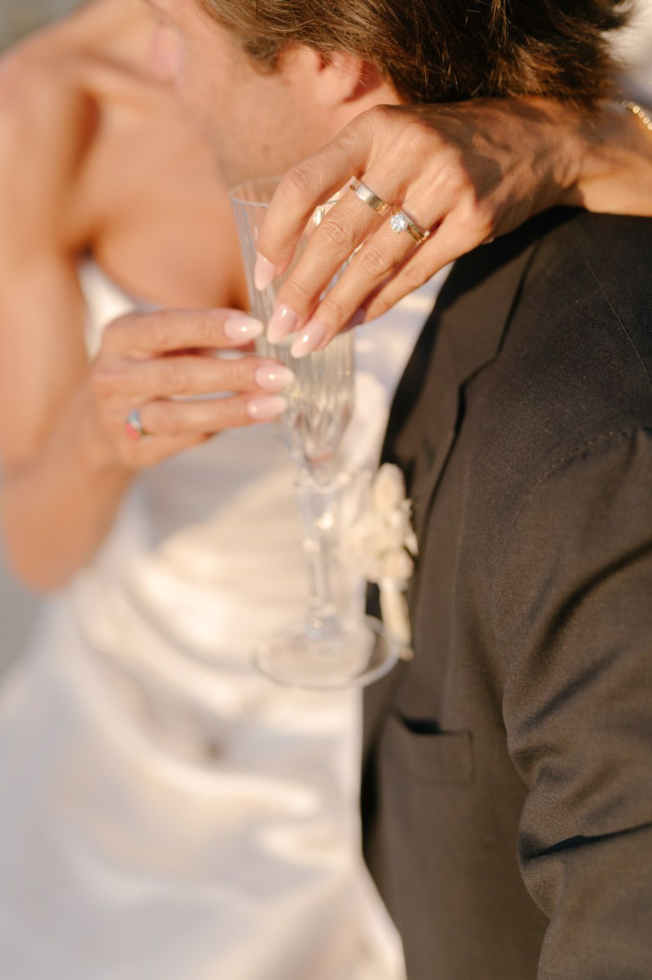 Close-up details of champagne glasses and formal attire at a wedding celebration.