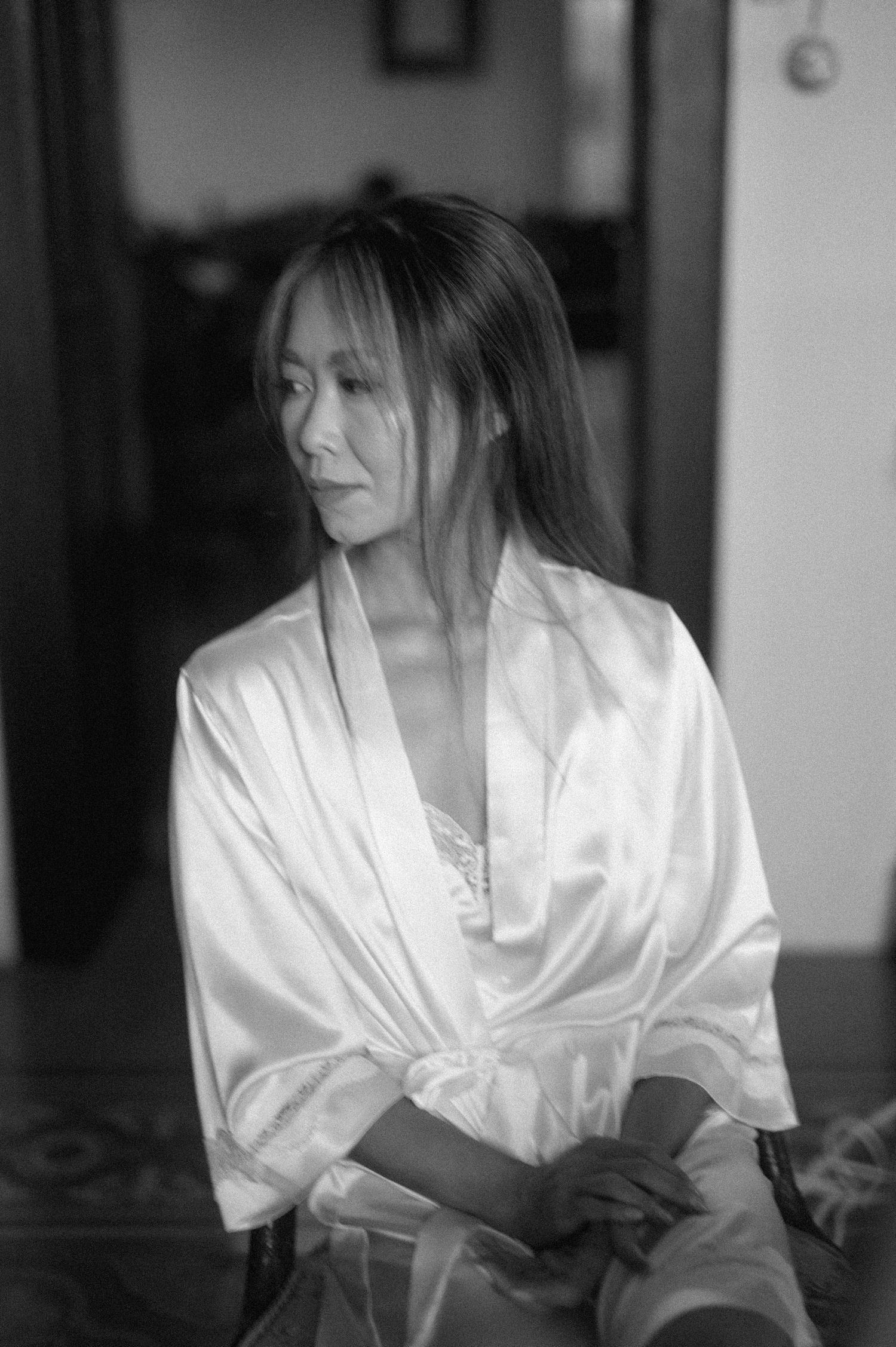 A series of black and white photos showing someone wearing a white silk robe in different poses against a dark background.