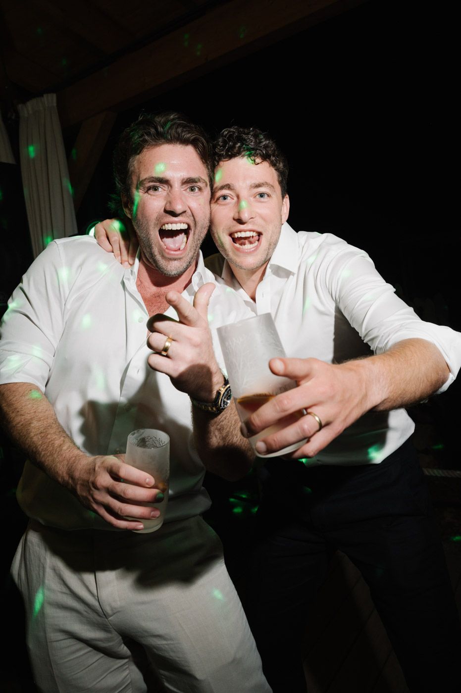 Groomsmen in white shirts posing and celebrating at a wedding reception.