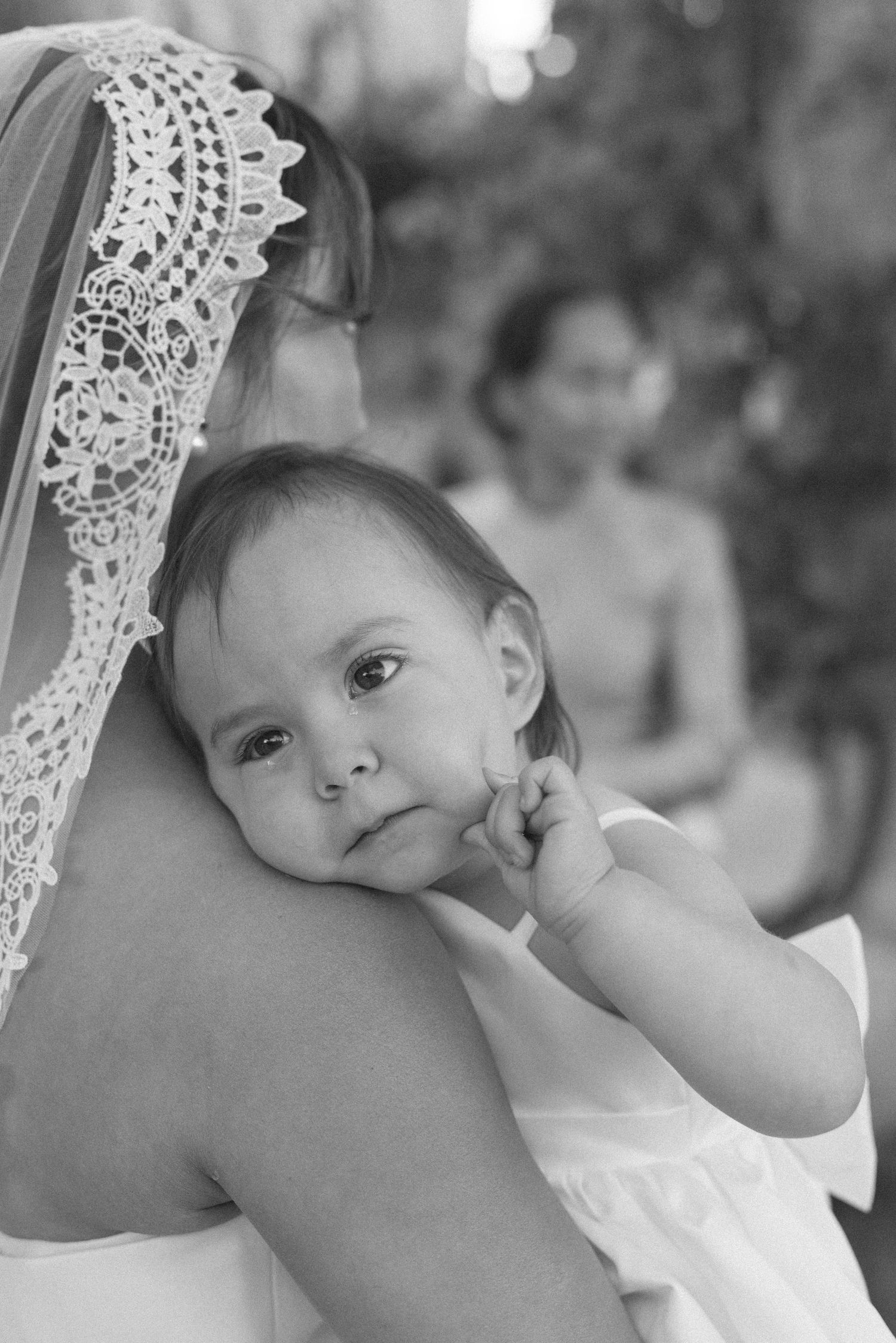 A series of black and white photos showing a baby in white lace being held against someone's shoulder.