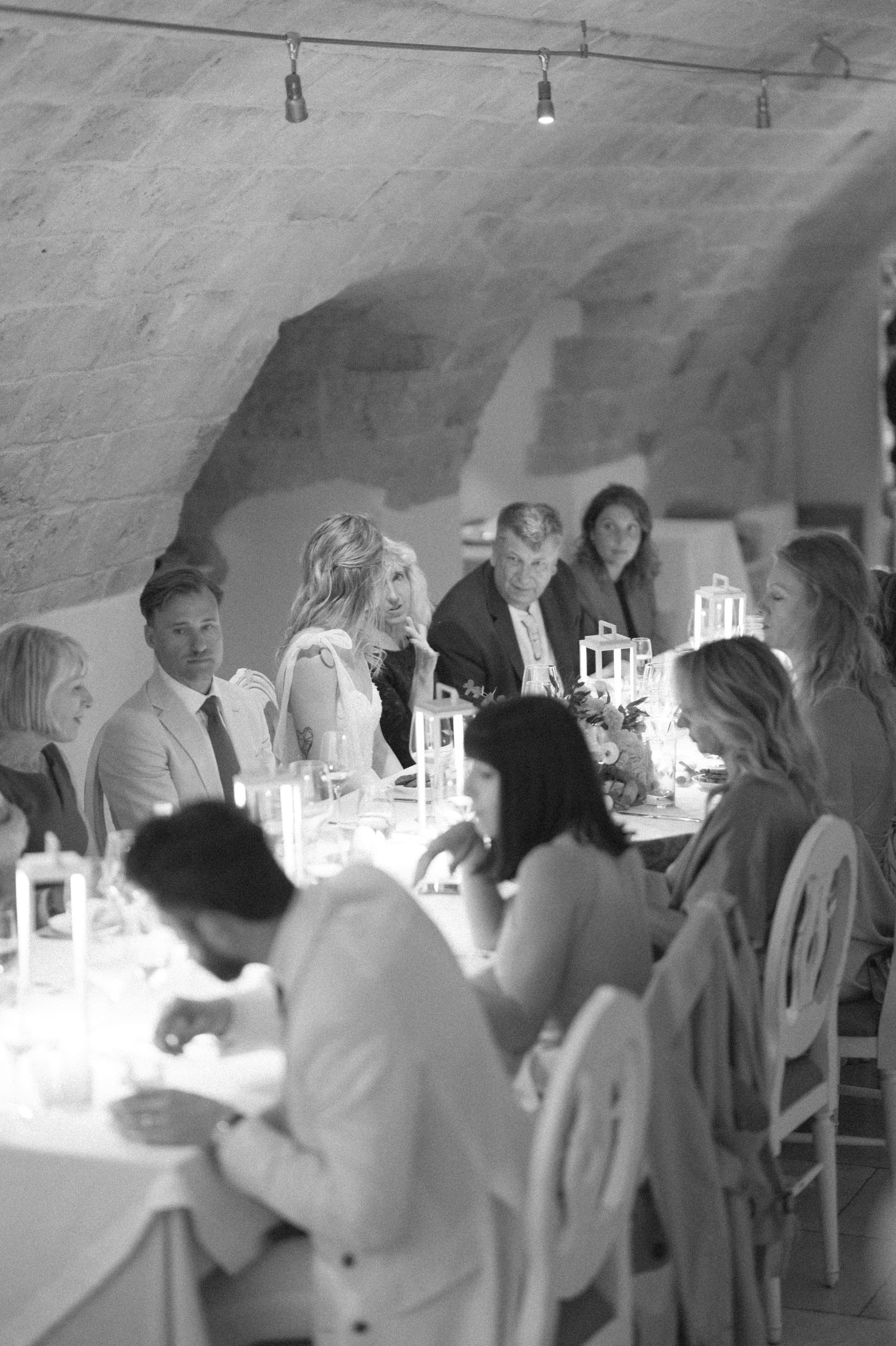 Black and white photo of wedding guests mingling and dancing at an indoor reception.