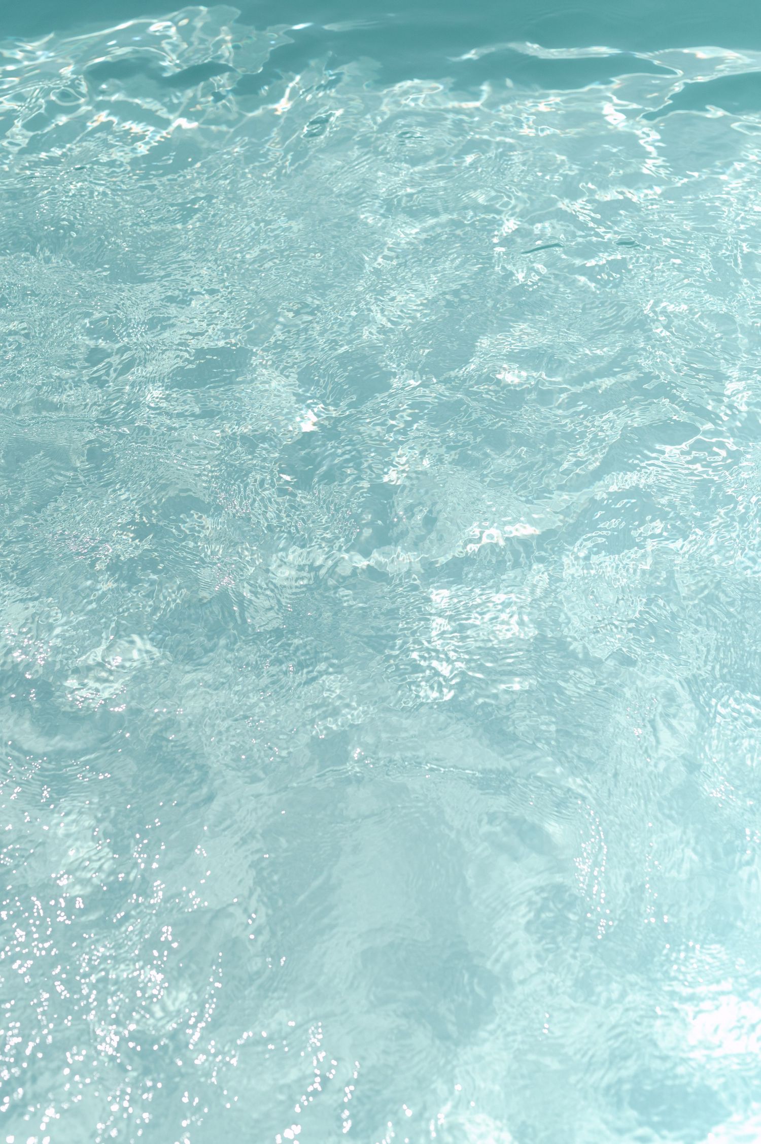 Crystal clear turquoise pool water with rippling surface reflections and sparkling sunlight creating a serene aquatic background.
