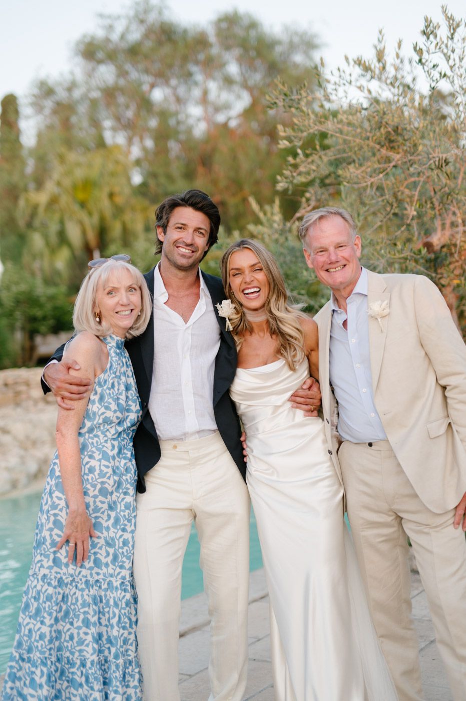 Wedding party in white and blue attire poses together outdoors.