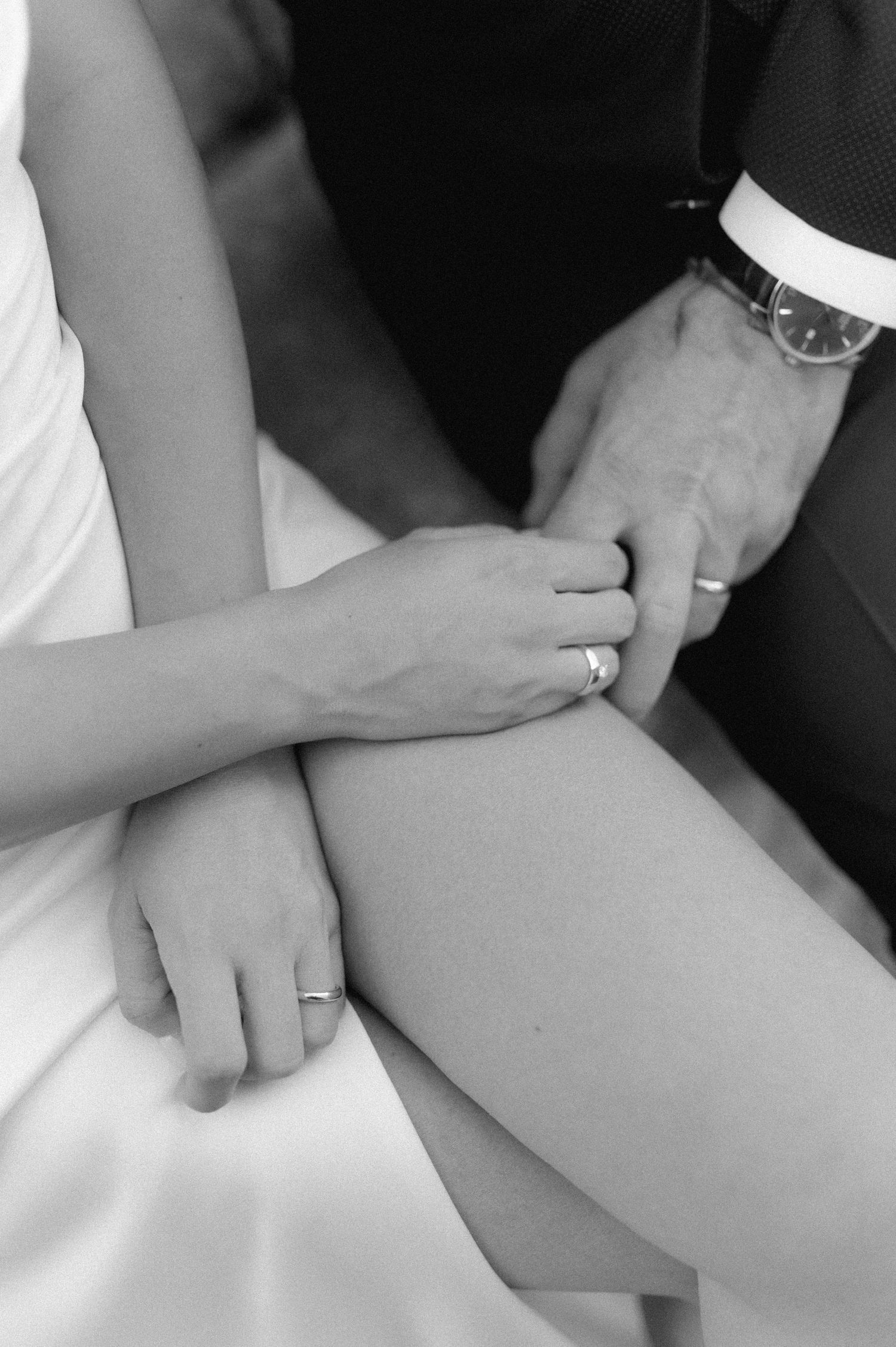 Close-up black and white photo of hands with wedding rings.