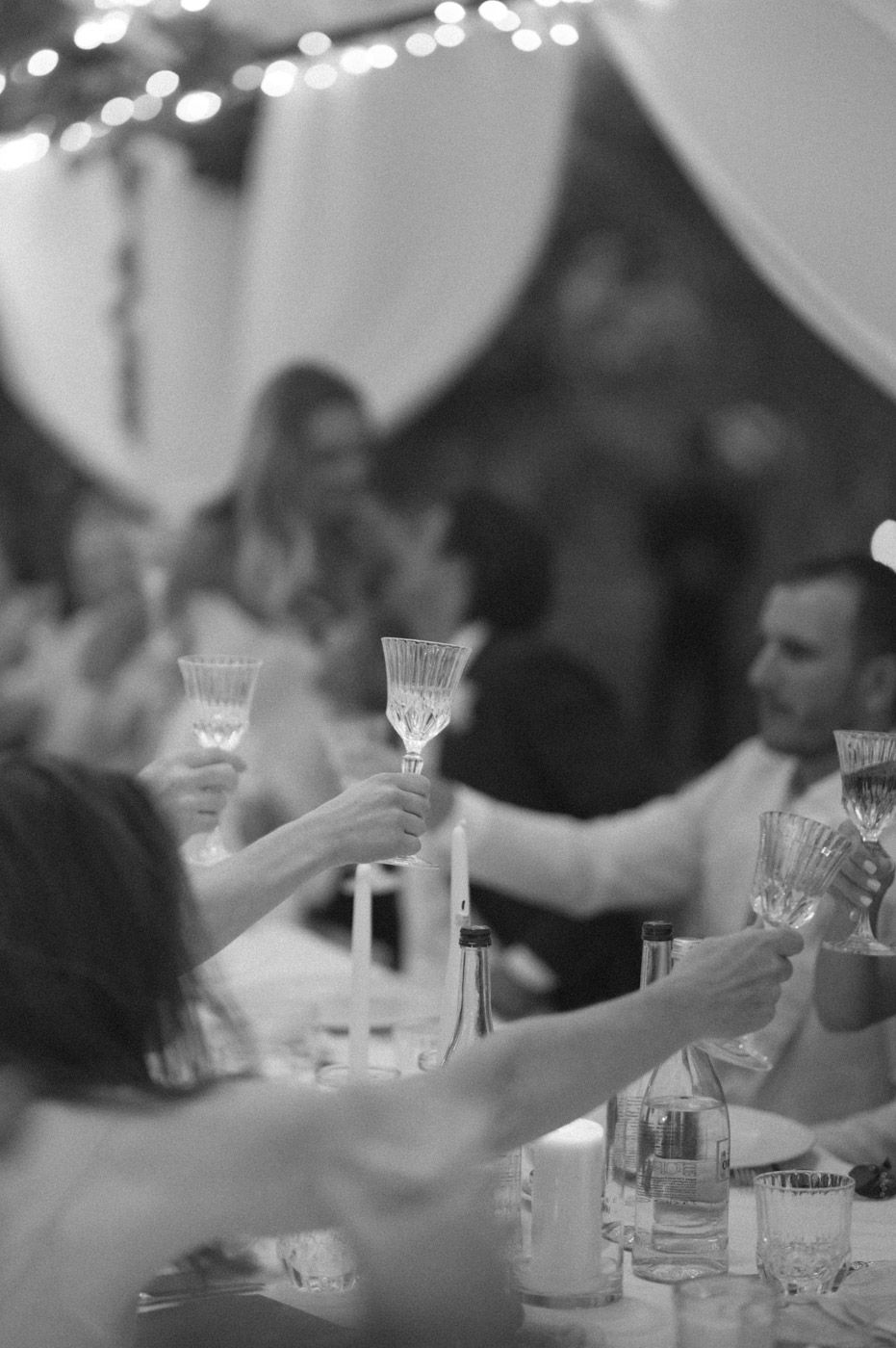 Crystal glasses and place settings line elegant tables at an outdoor wedding reception.