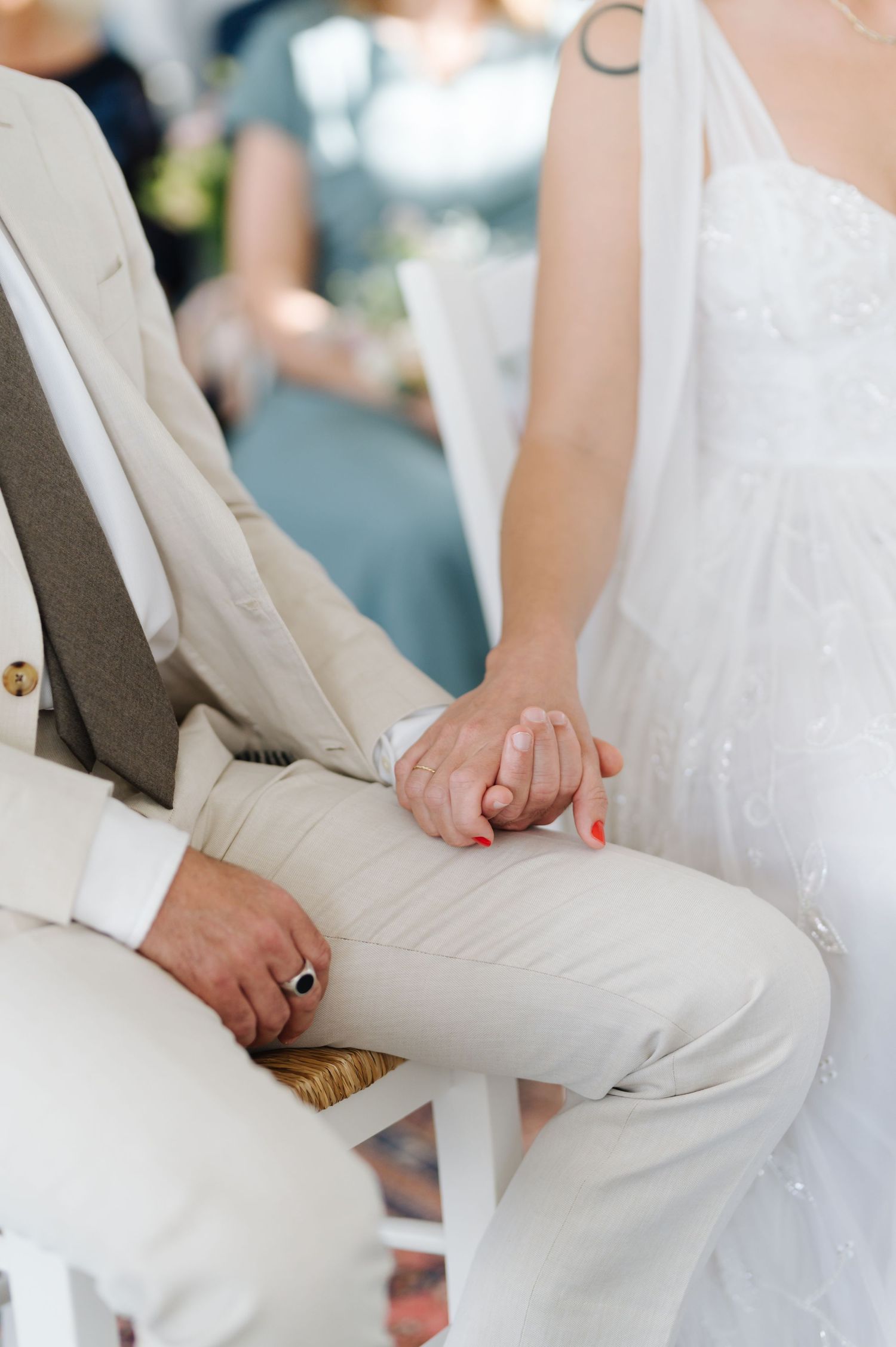 Detail shots of white formal attire and hands during a special occasion.