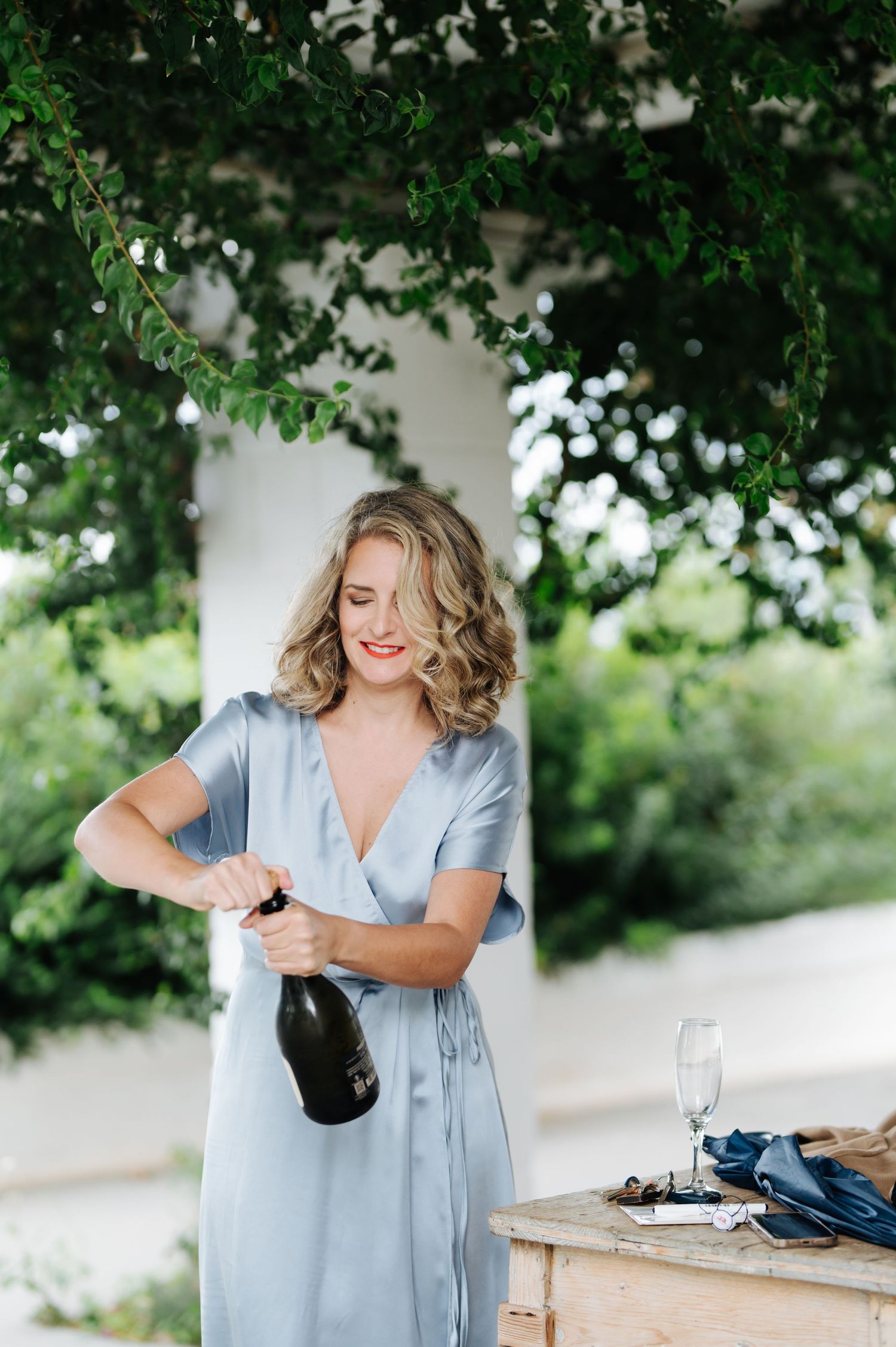 Light blue dress and champagne pouring scene in an outdoor setting.