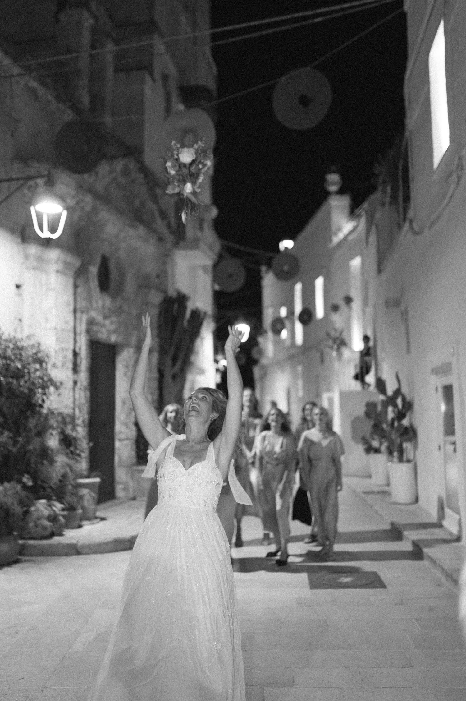 Nighttime wedding photography on a romantic stone-paved street with glowing lamps.