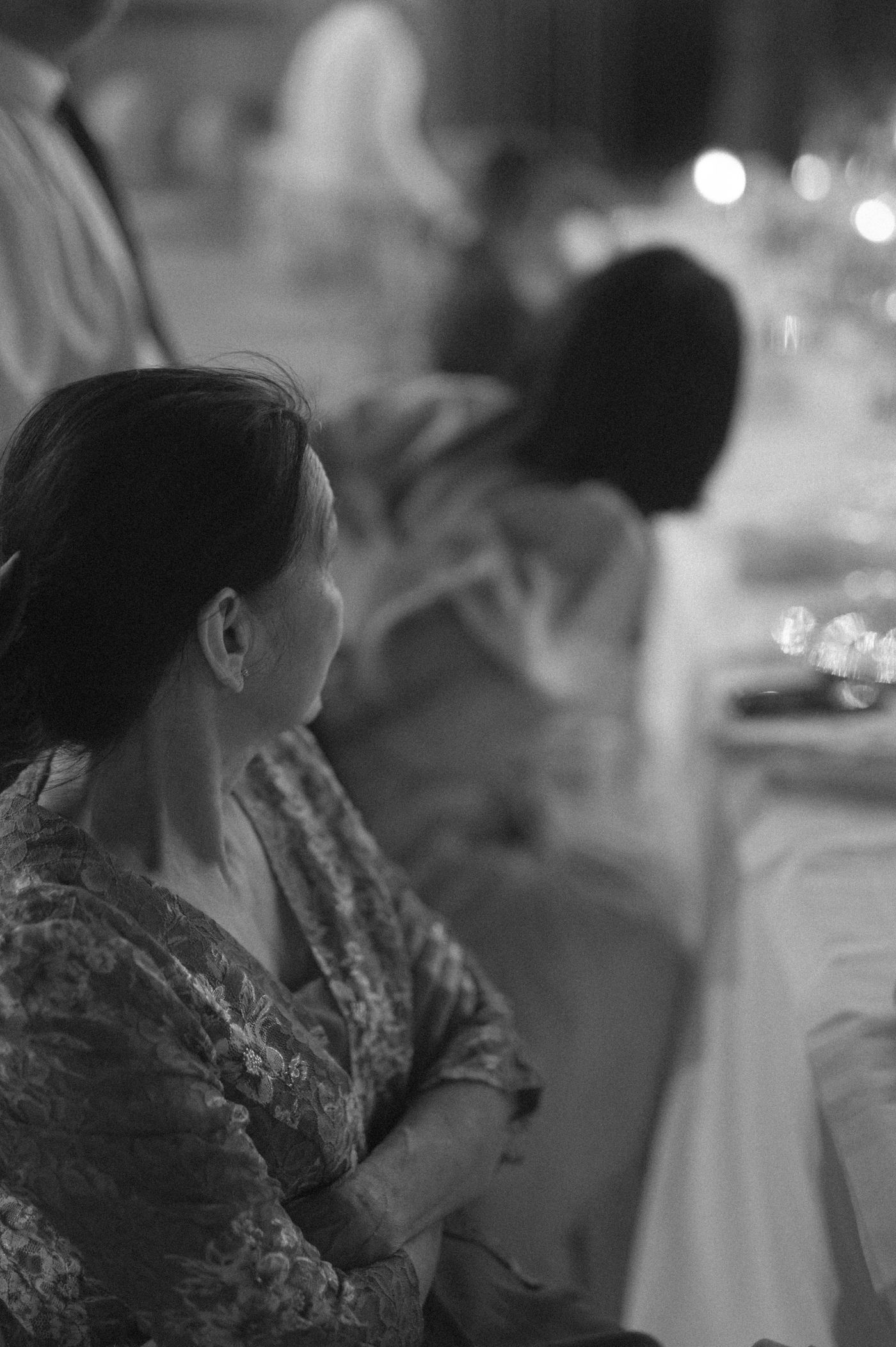 Black and white photo of a person in a patterned dress seated at a formal dining event.