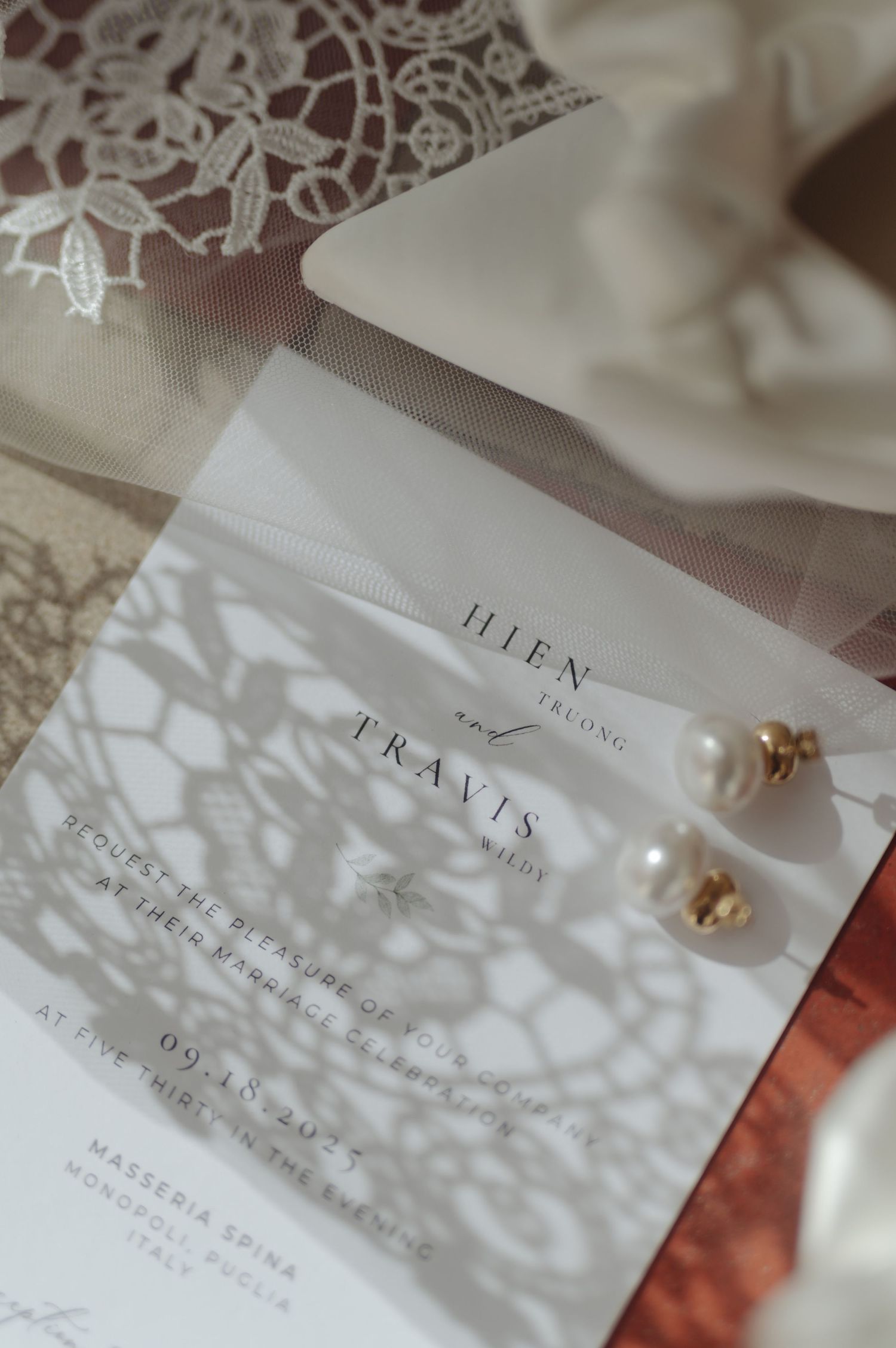 Wedding invitation details with delicate lace shadow patterns and elegant typography on white paper.