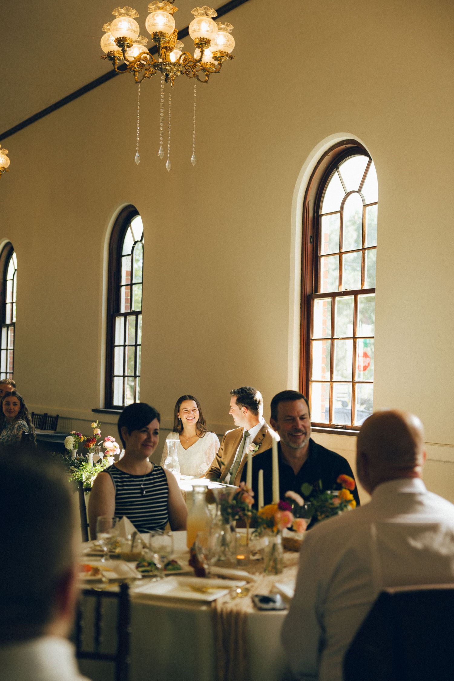 Candid shots of guests dining and socializing at an elegant reception with arched windows and warm lighting.