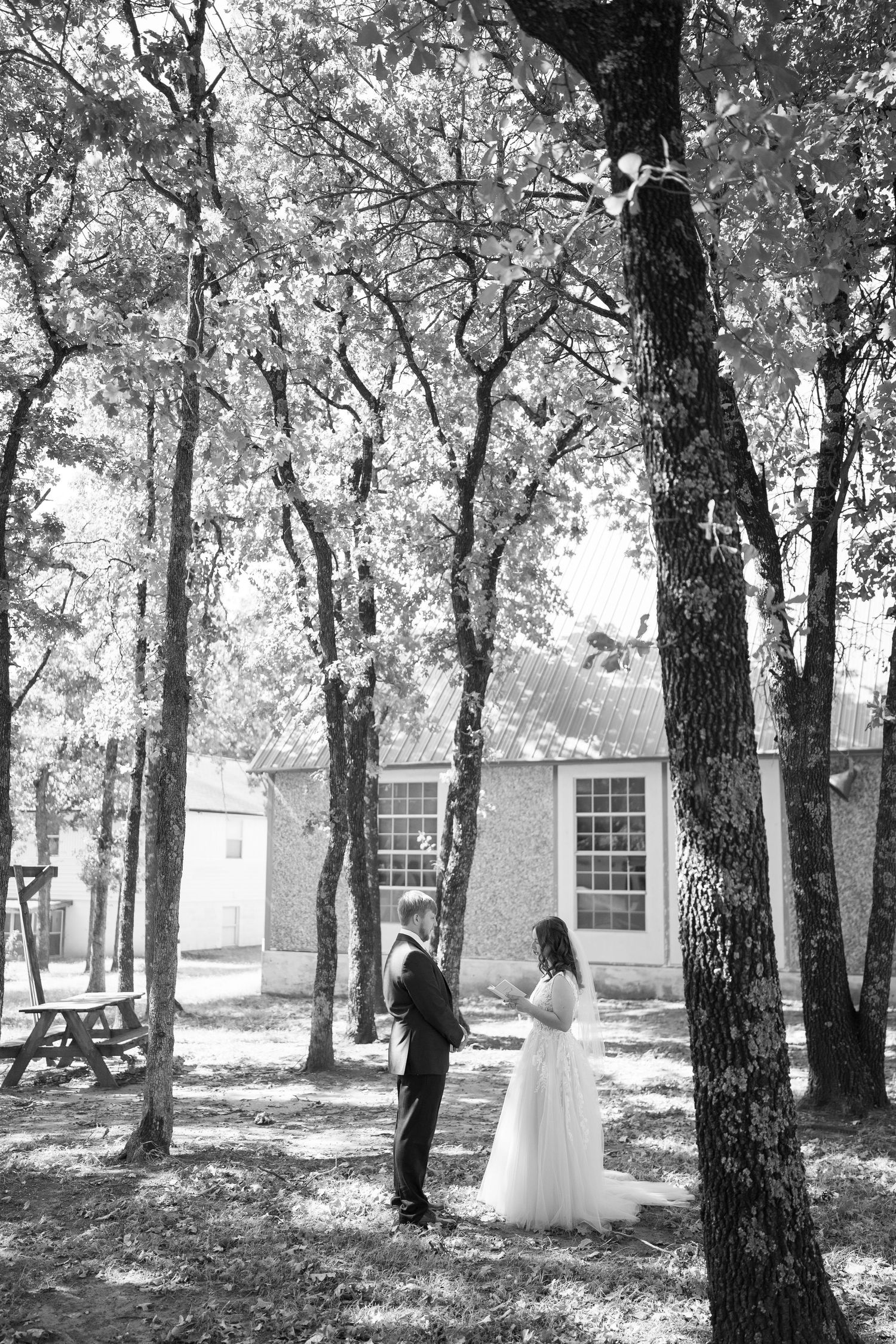 Black and white wedding portraits captured among trees in a peaceful outdoor setting.