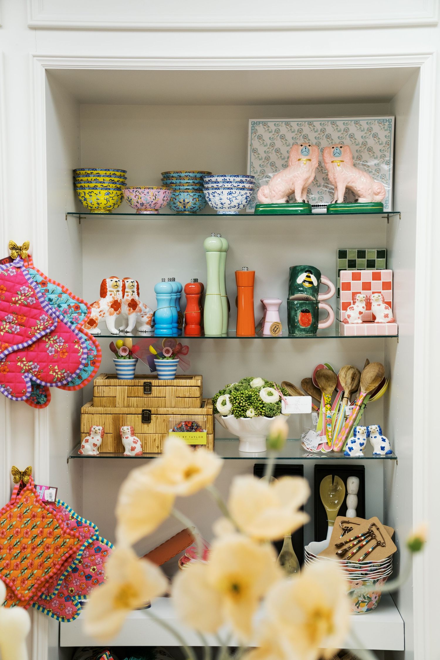 Organized retail shelves displaying colorful kitchenware, glassware, and decorative items in a modern home goods store.