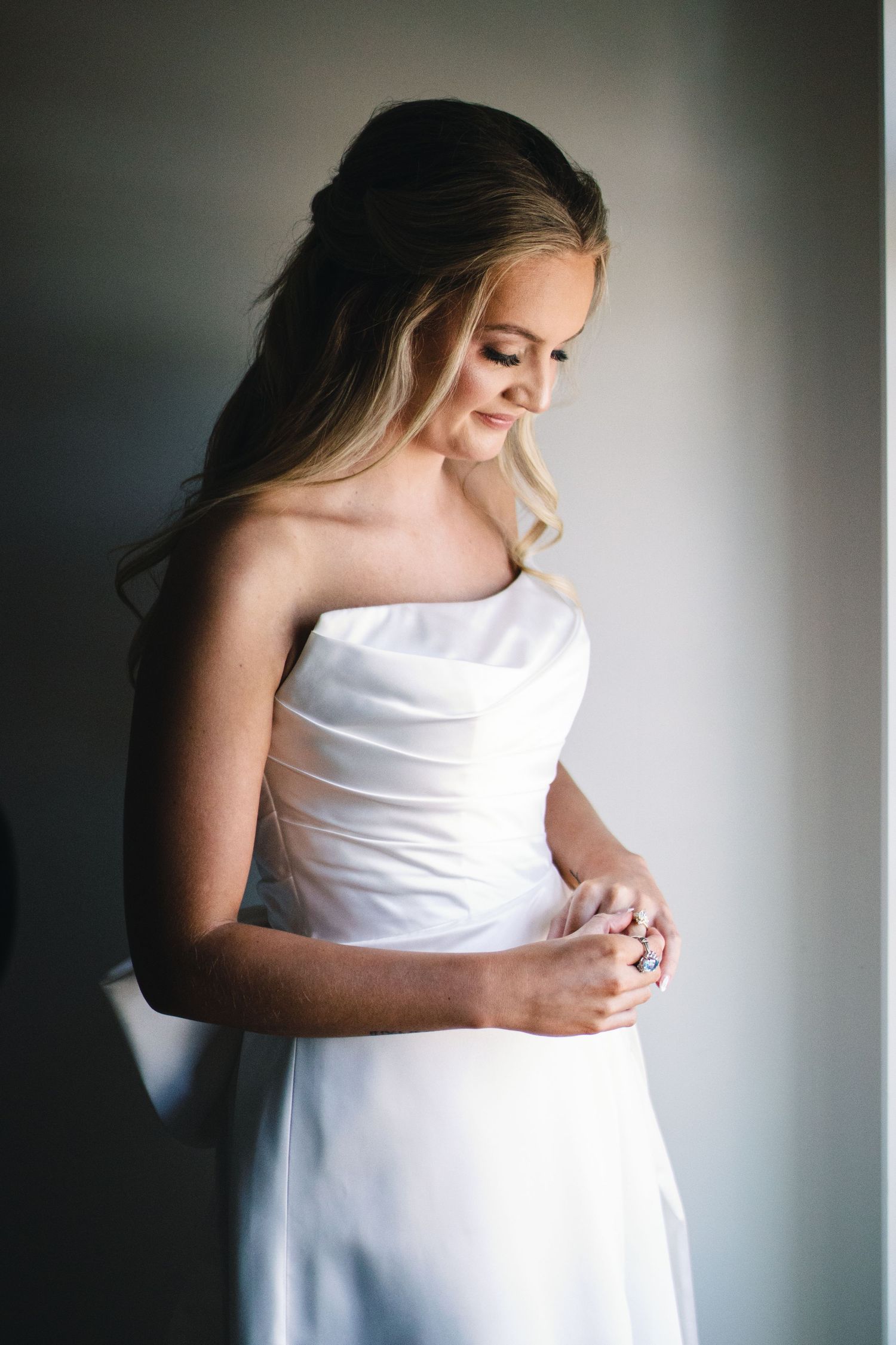 Artistic bridal portrait series against dramatic lighting and grey background.