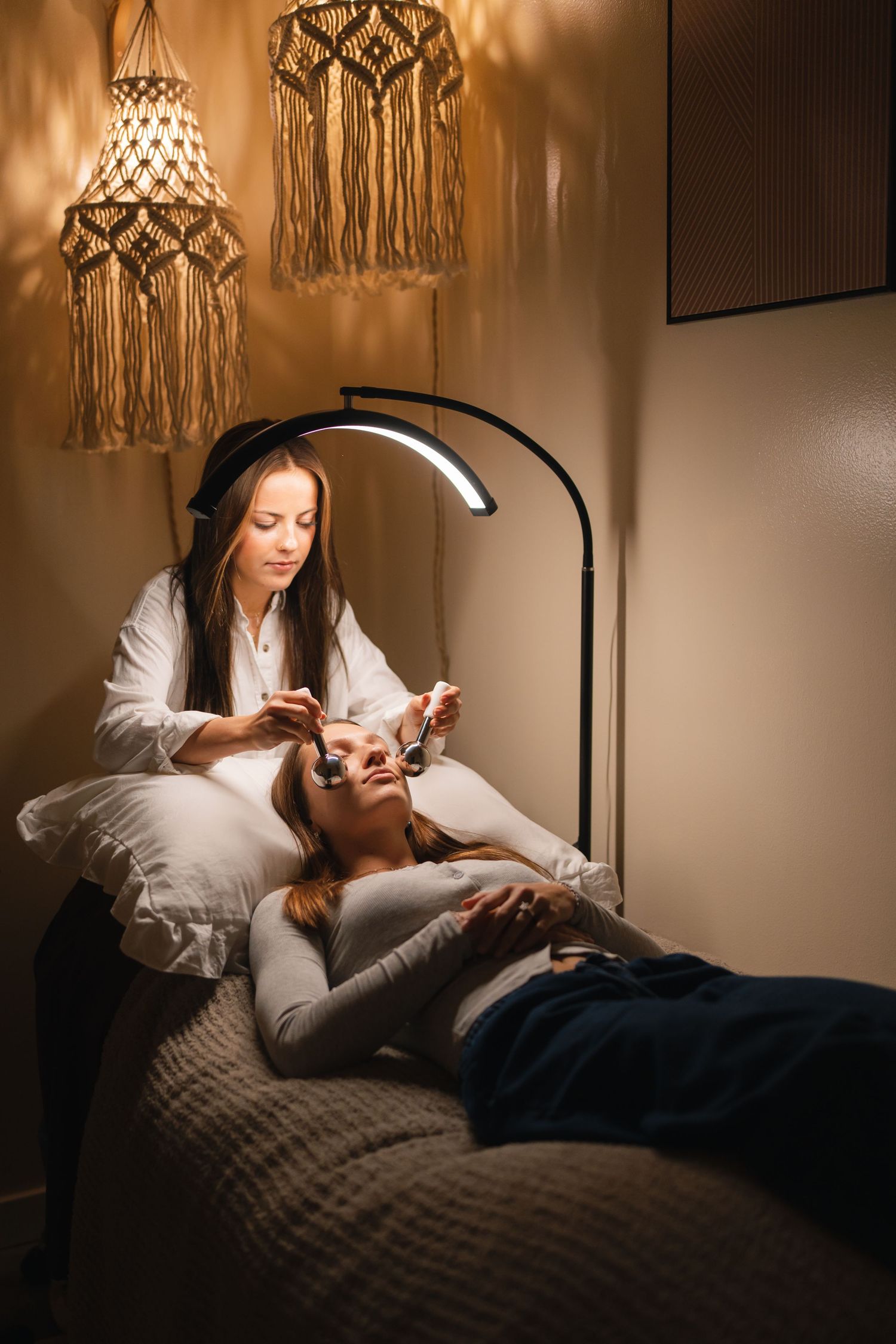 Person relaxing in bed with warm mood lighting and macrame wall hangings creating a cozy atmosphere.