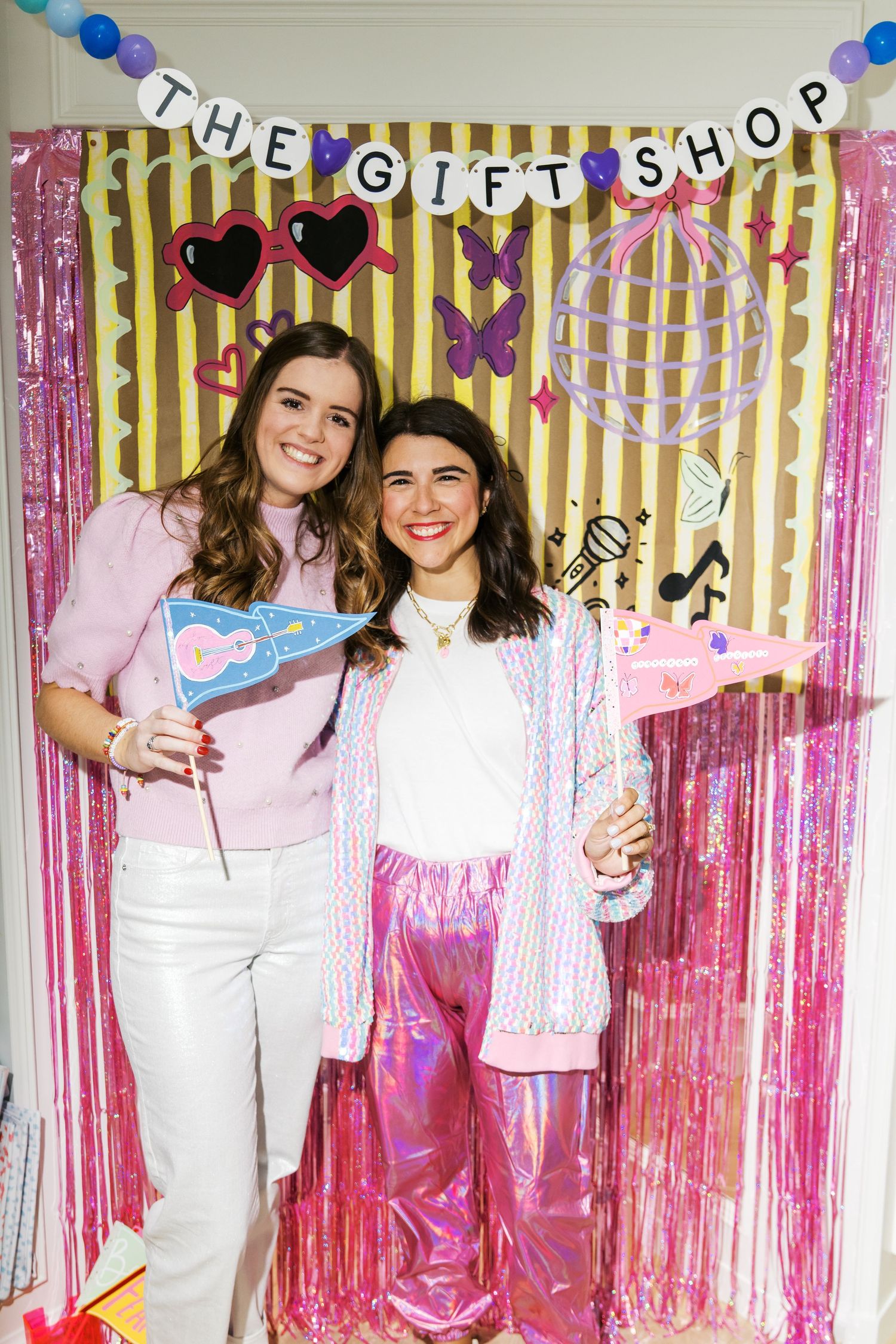 Party scene with pink and gold striped backdrop decorated with metallic streamers and festive banners.