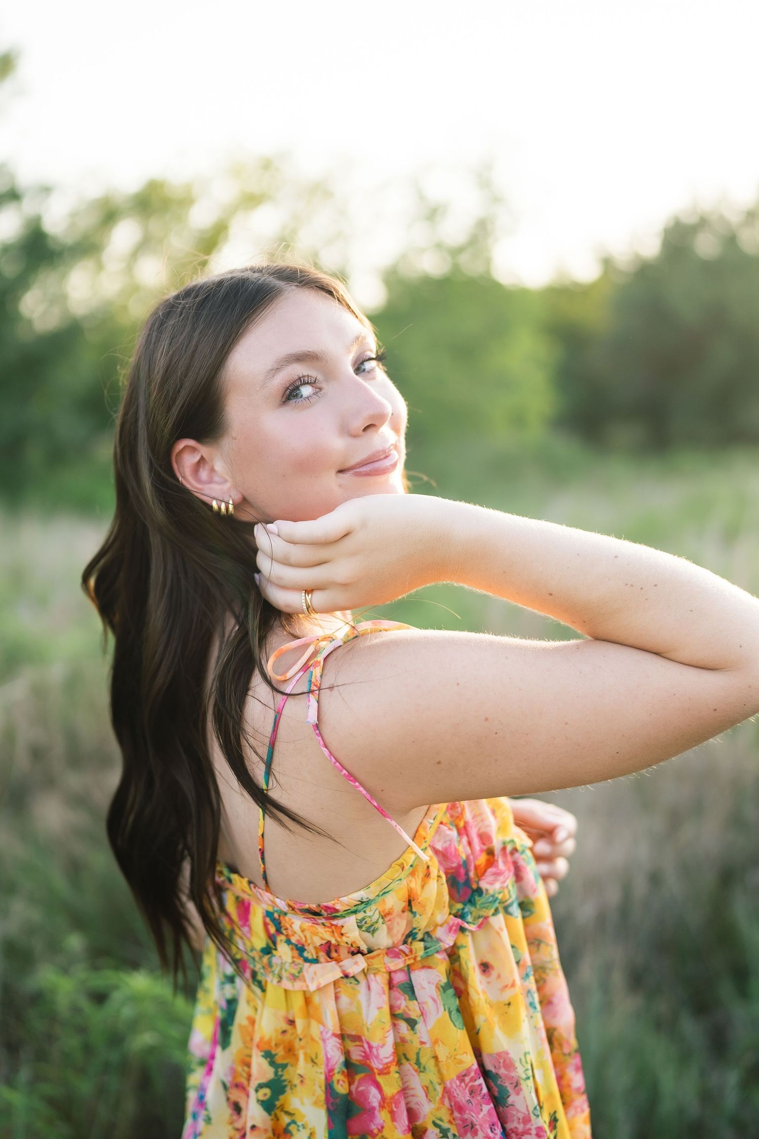 Summer portraits in a floral dress with soft natural lighting among foliage.