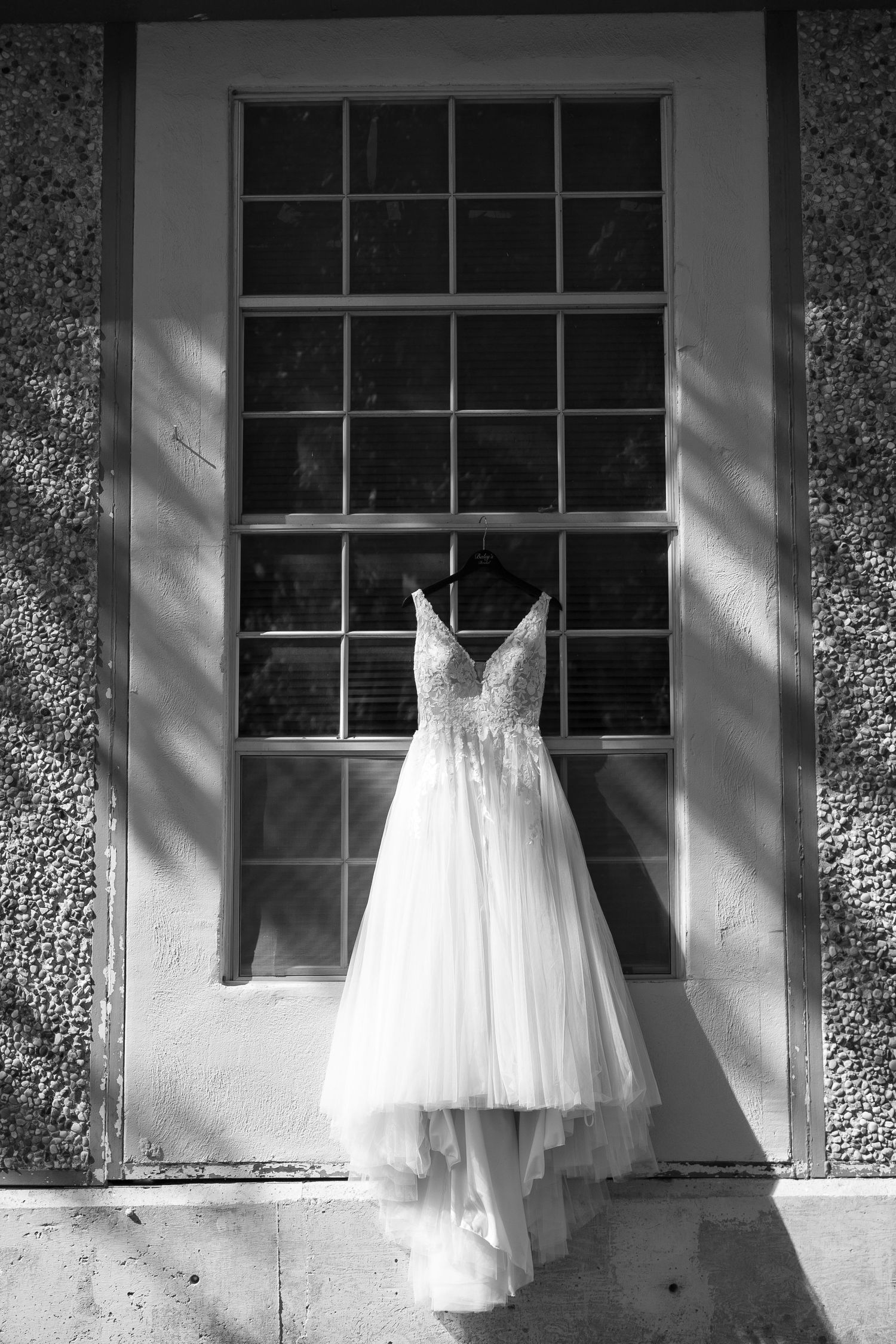 Black and white series of white wedding dresses hanging in windows creating an artistic display.