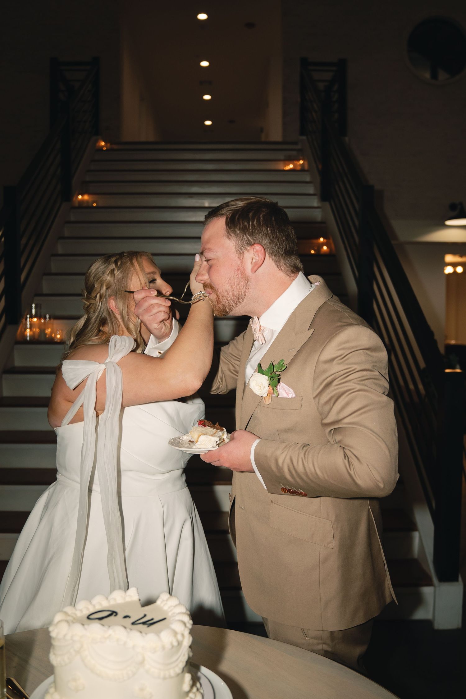 Wedding couple shares playful moment during reception dance in dimly lit venue.