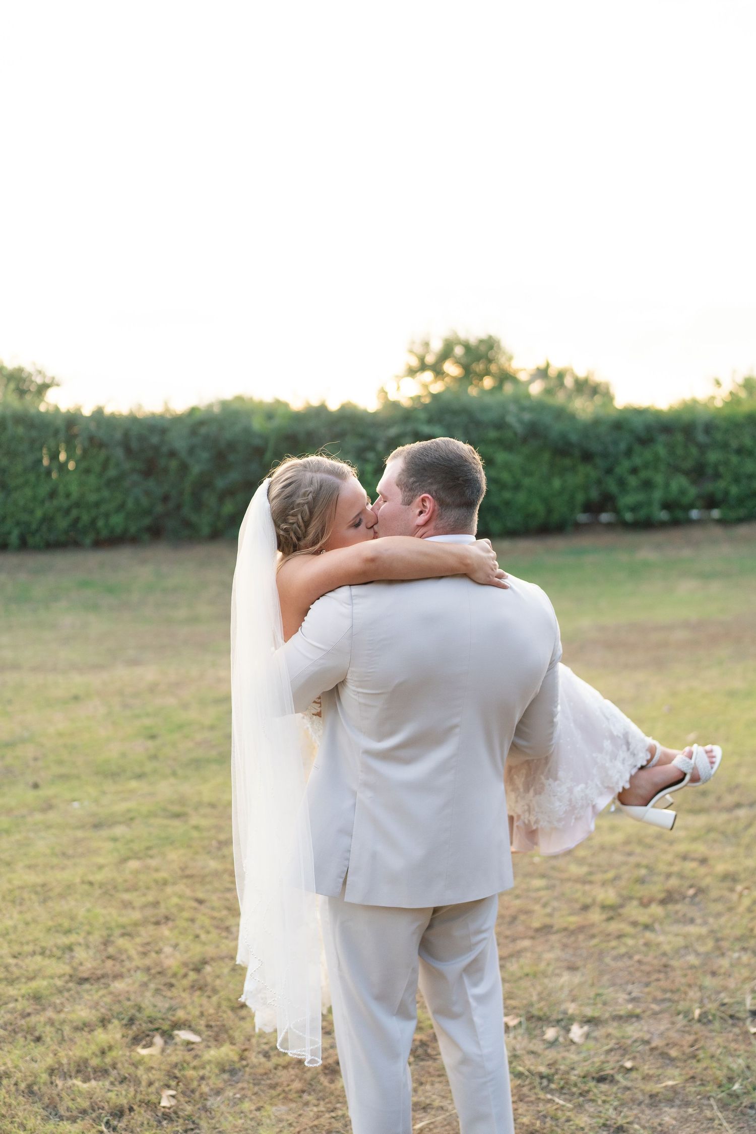 Newlywed couple shares a romantic moment during sunset in an outdoor field.