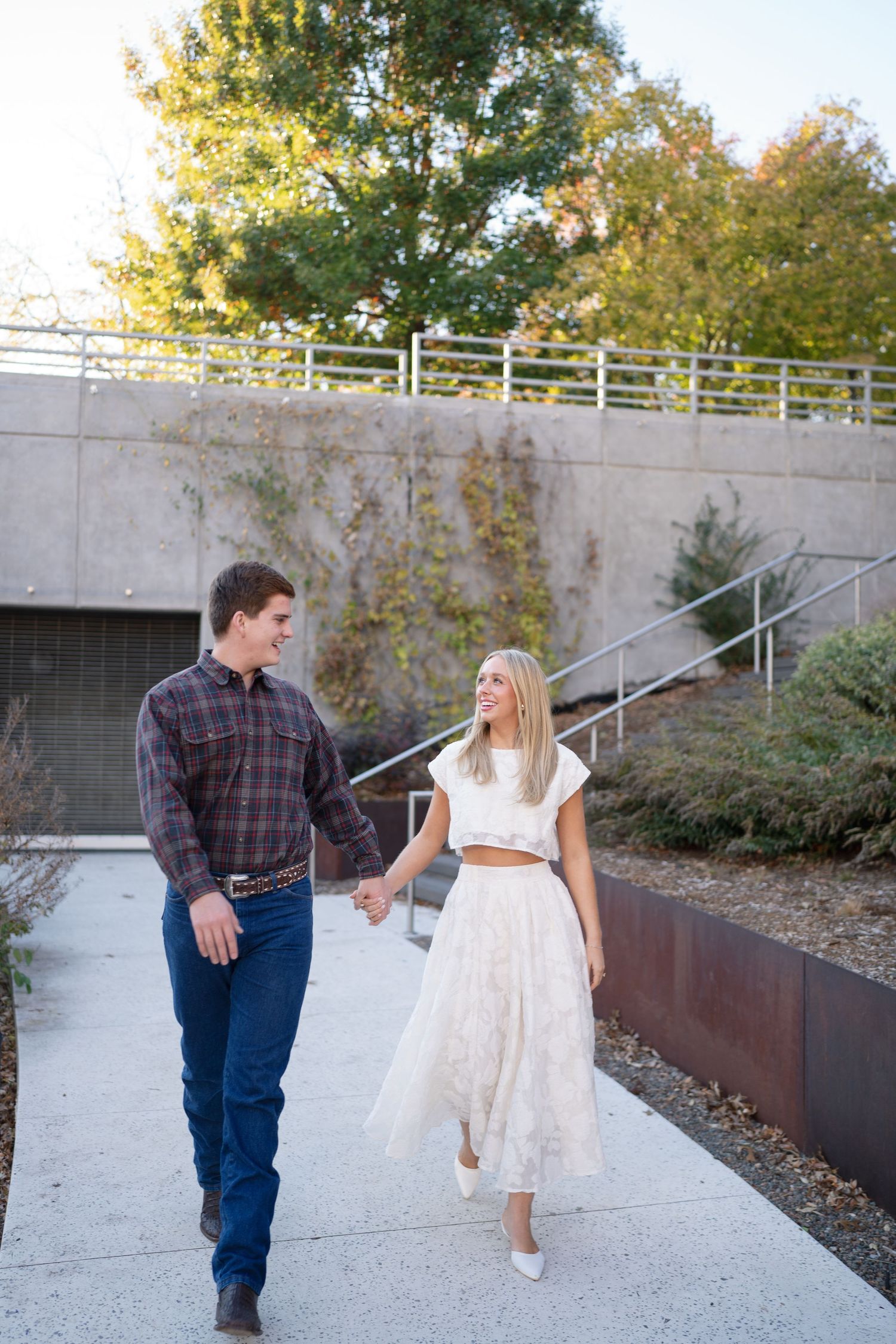 A couple shares a dance moment on concrete steps surrounded by autumn foliage.