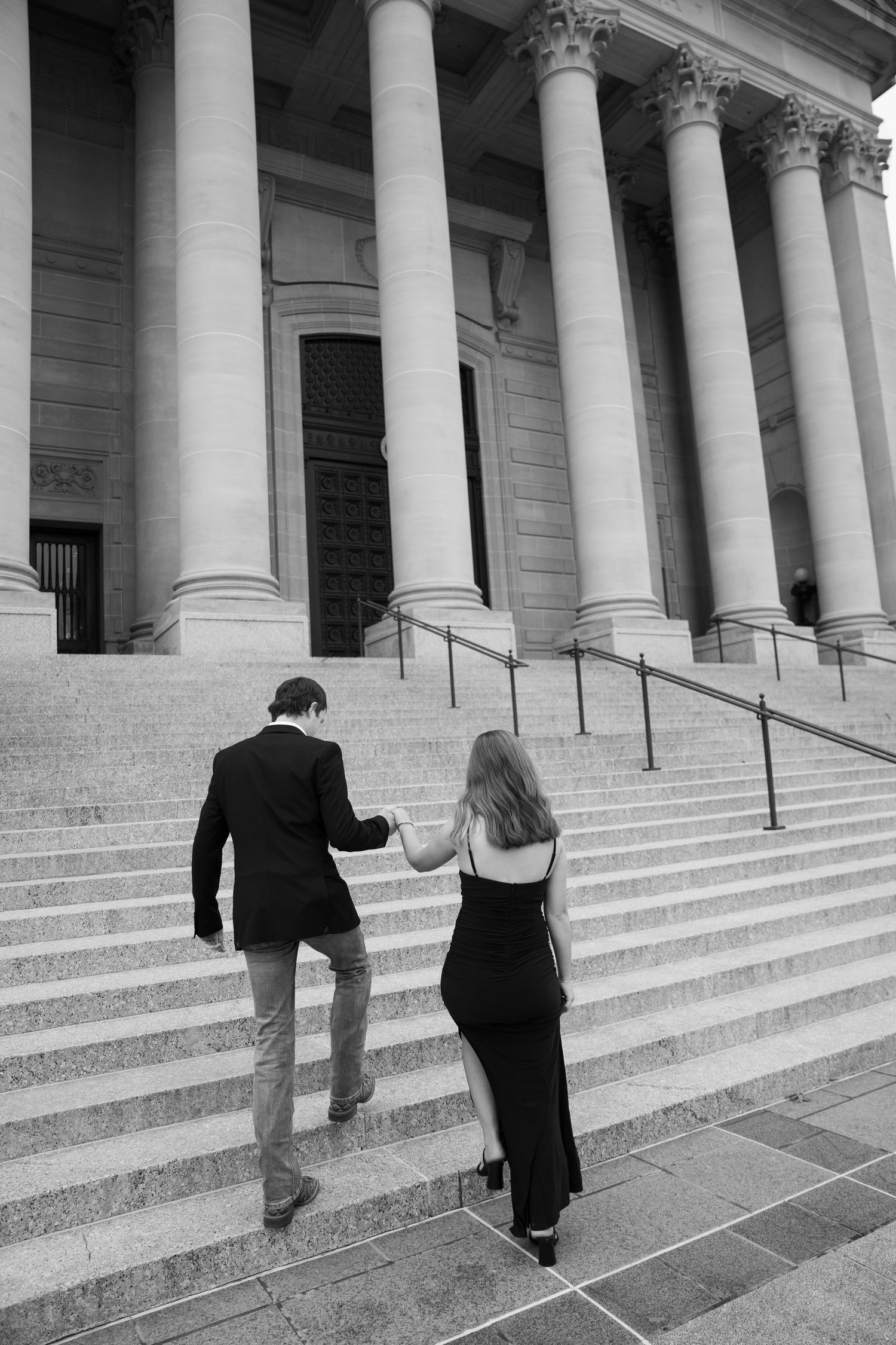 A grand building entrance with white columns and stone steps in black and white photography.