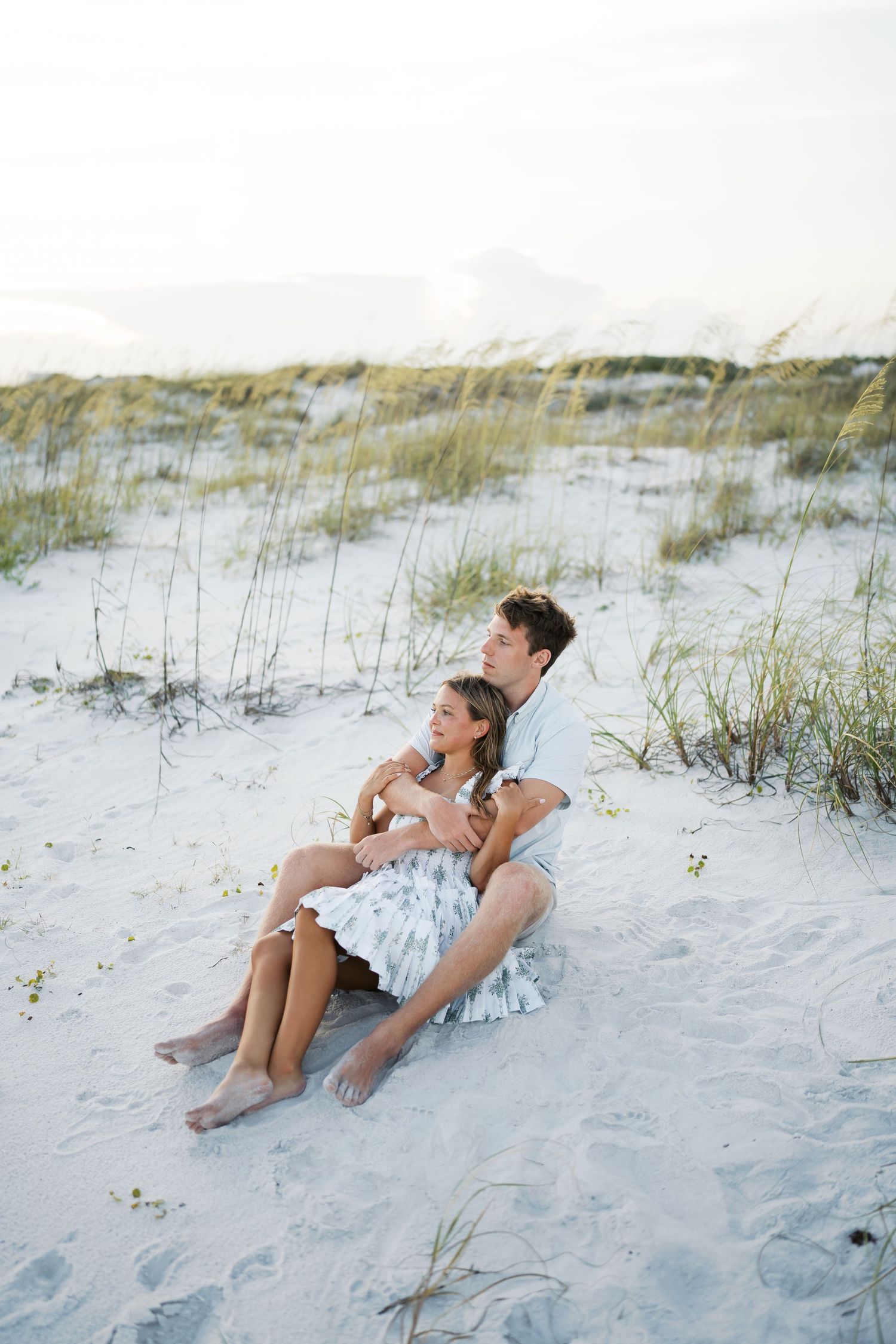 Couple relaxing together on white sandy beach dunes.