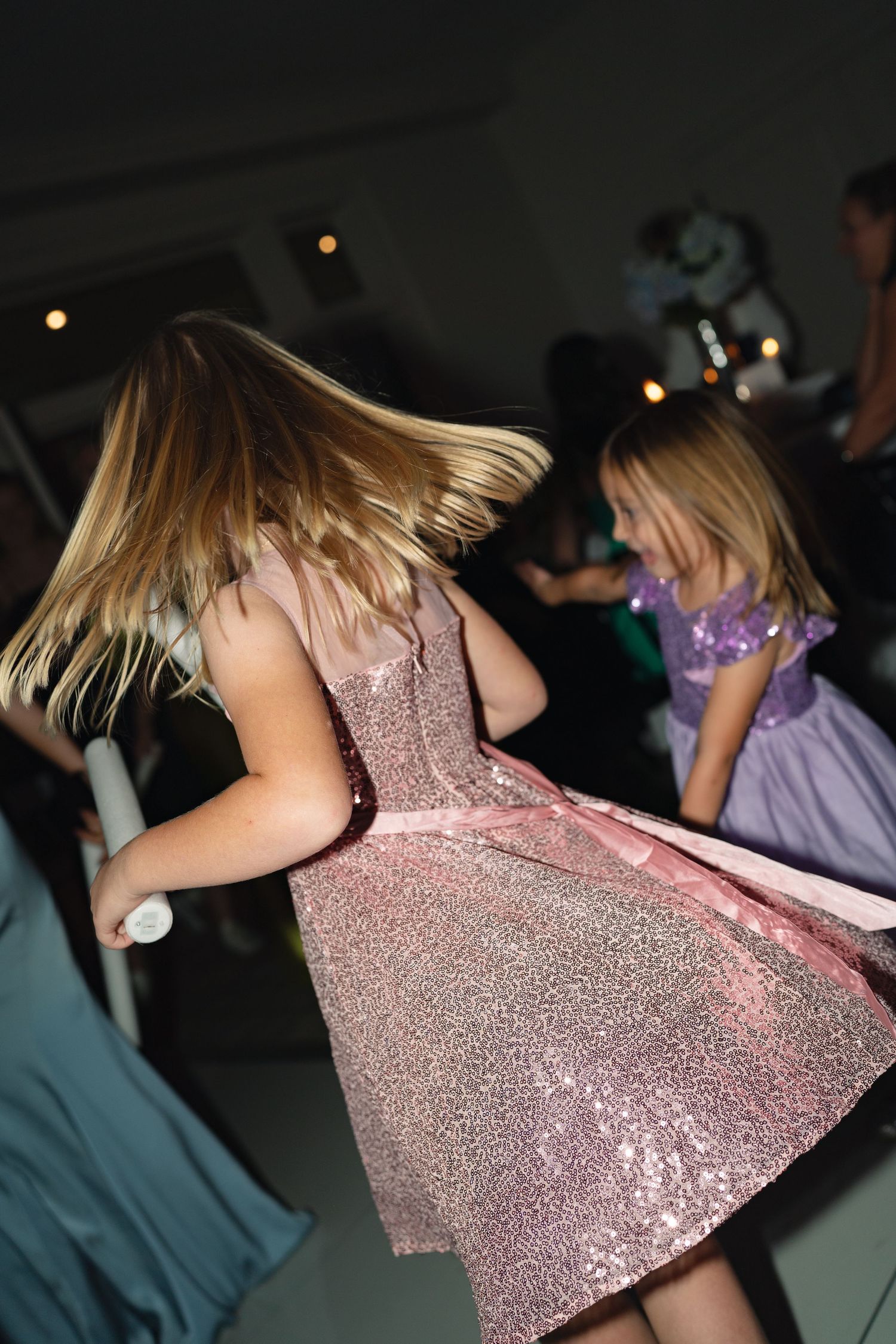 A guest in a sparkly pink dress dances at a wedding reception.