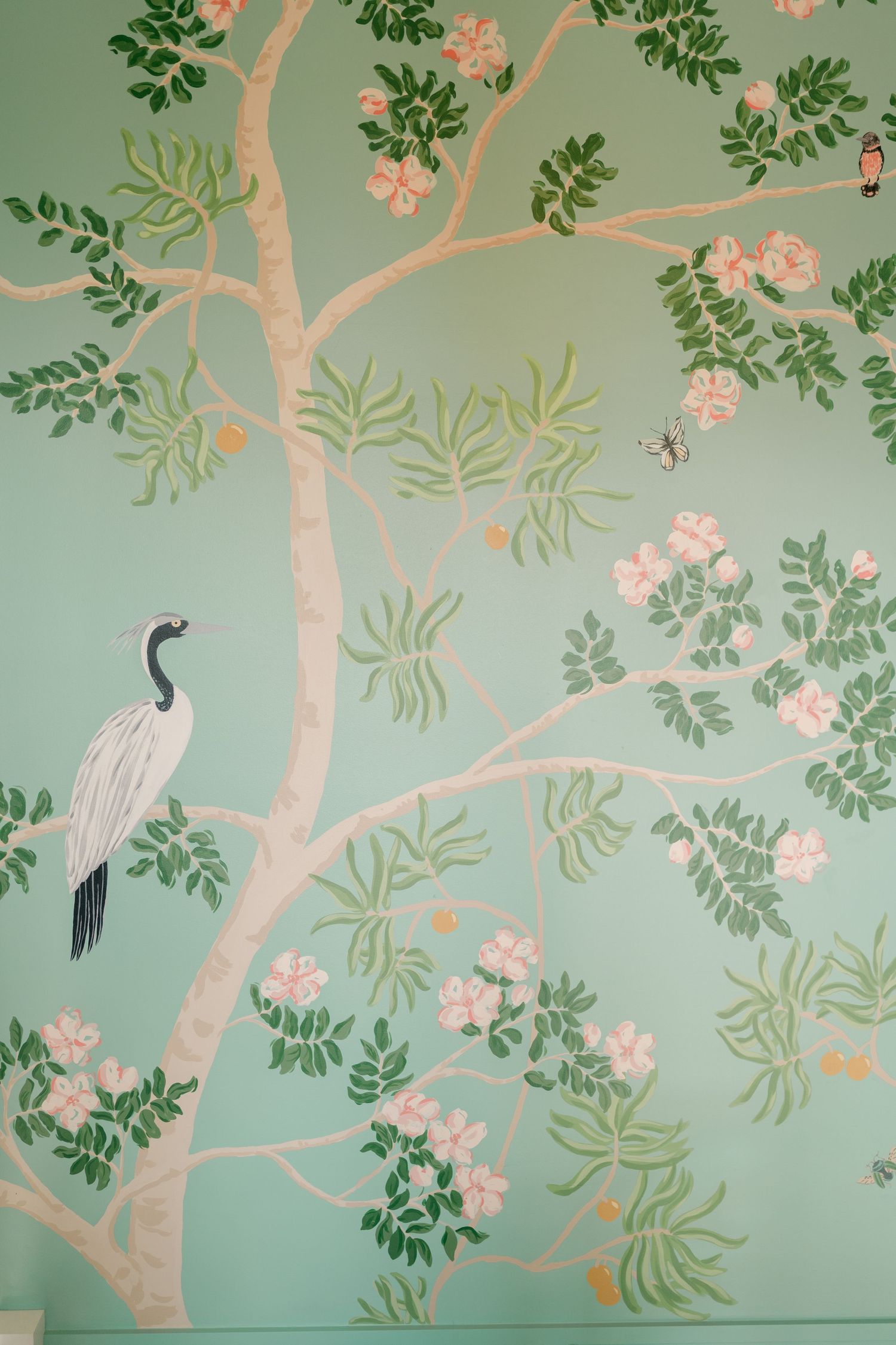 Chinoiserie wallpaper mural featuring a white crane, pink blossoms, and green foliage on a mint background.