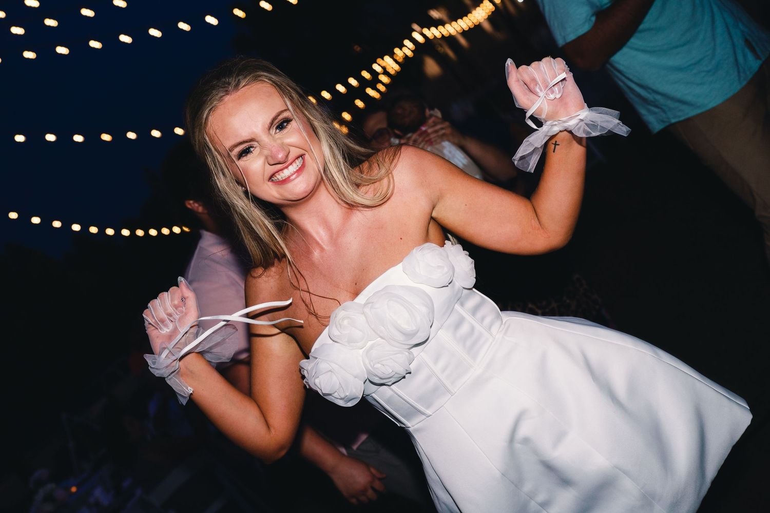 Wedding reception dance floor lit by string lights at night.