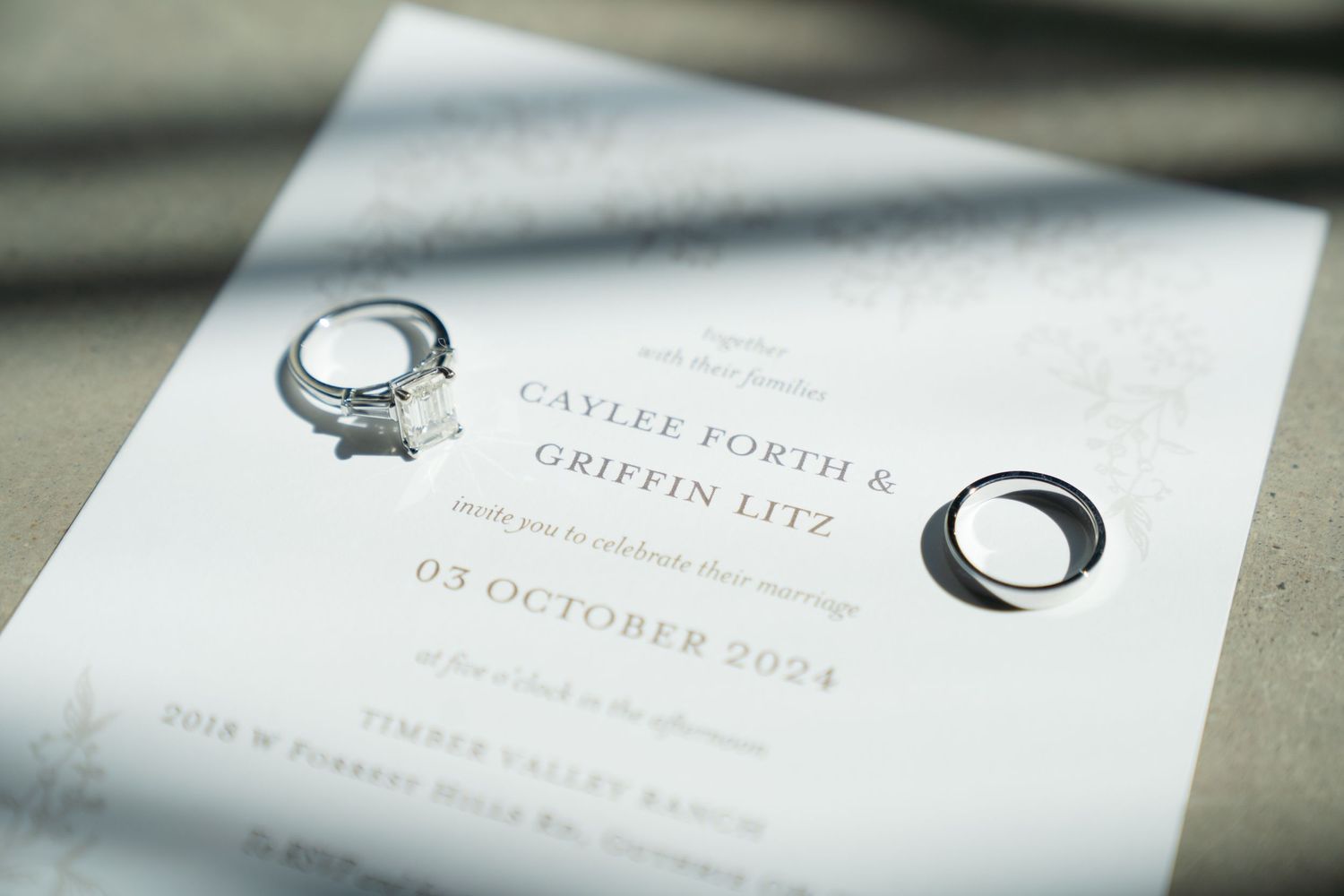 Wedding invitation with rings photographed in soft natural light showing wedding date details.
