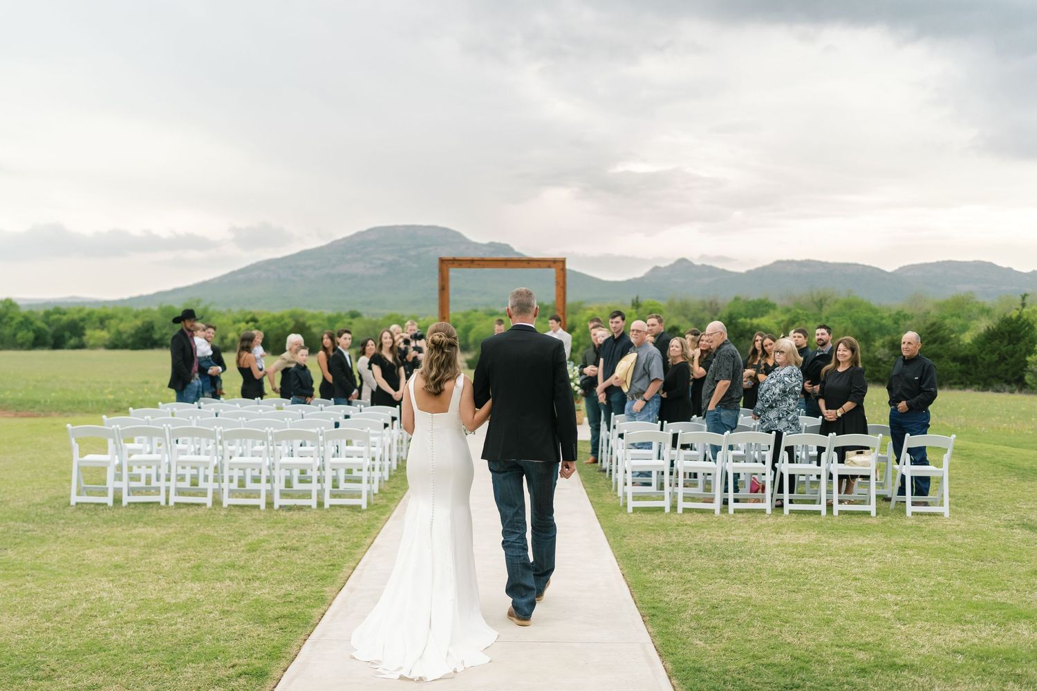 White chairs arranged outdoors for a wedding ceremony with mountains in the background.