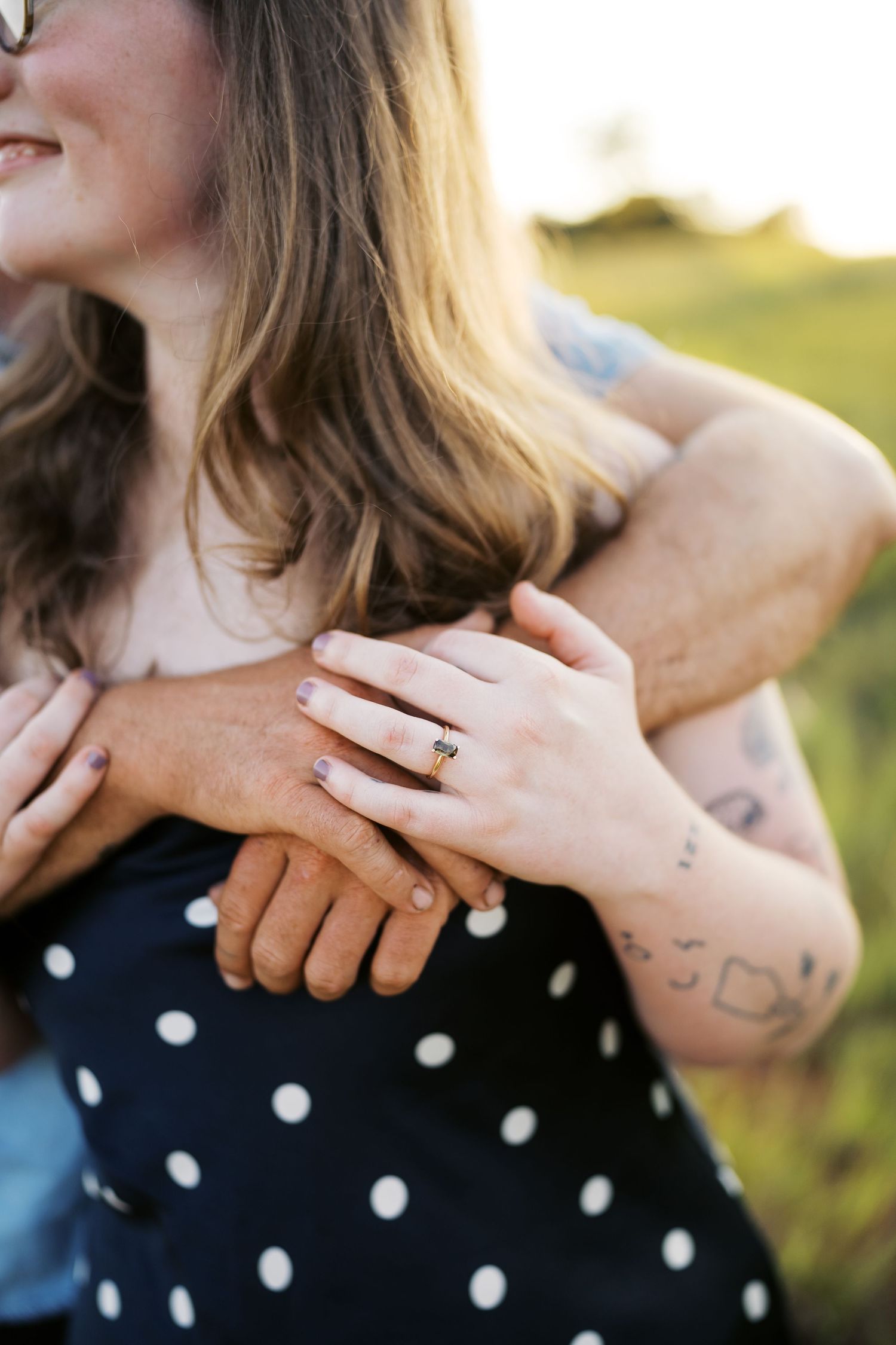 Close-up of hands showing wedding ring against polka dot dress.