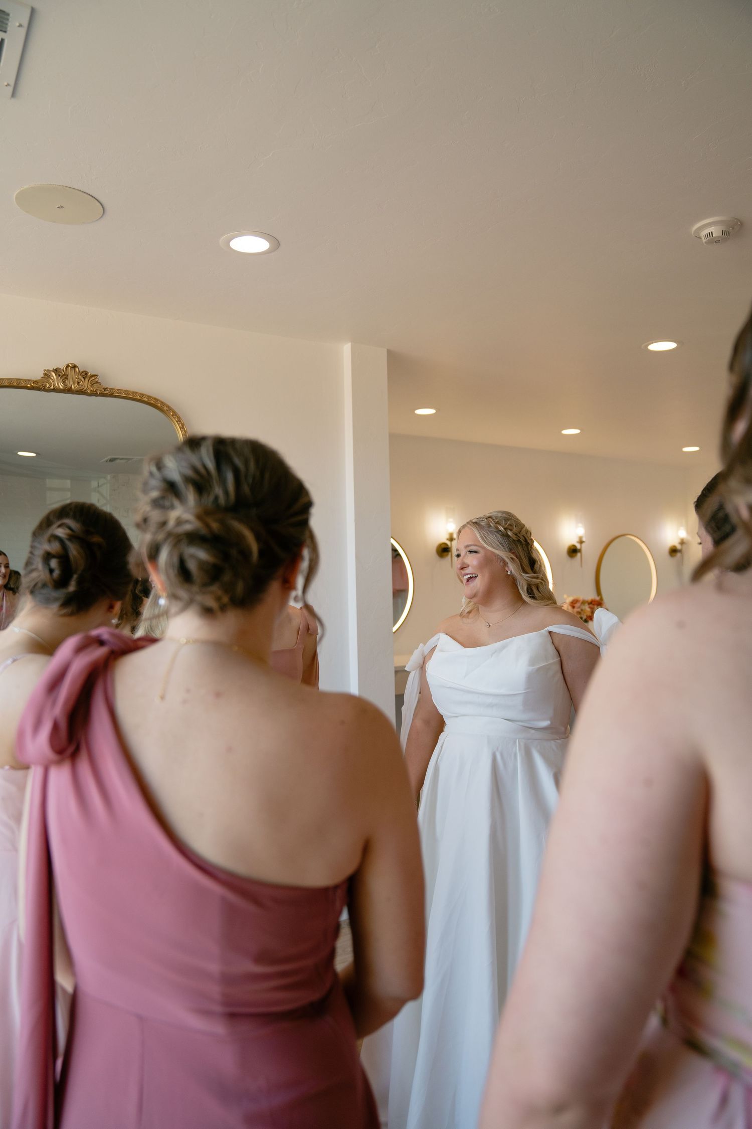 Bridesmaids in mauve dresses getting ready in front of mirrors.