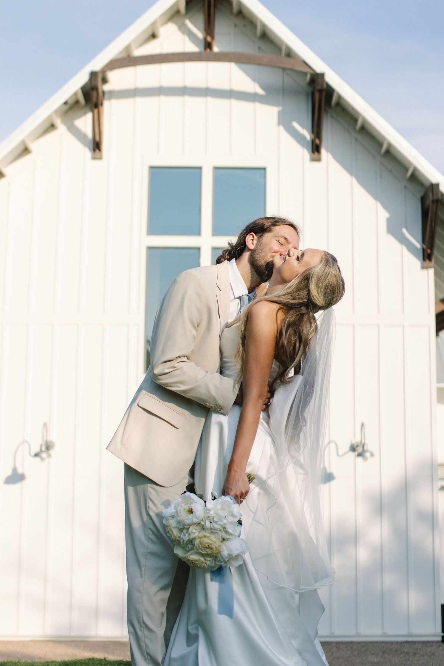 Romantic wedding portraits against white chapel wall in natural light.