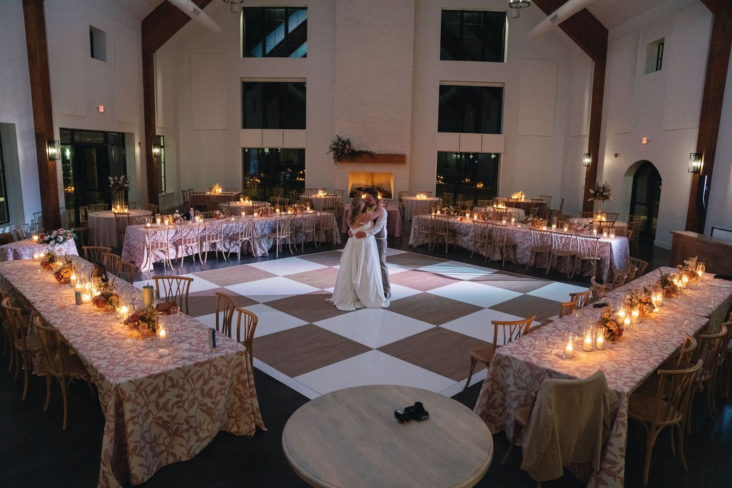 Large wedding reception hall with white linens and glowing candlelight.