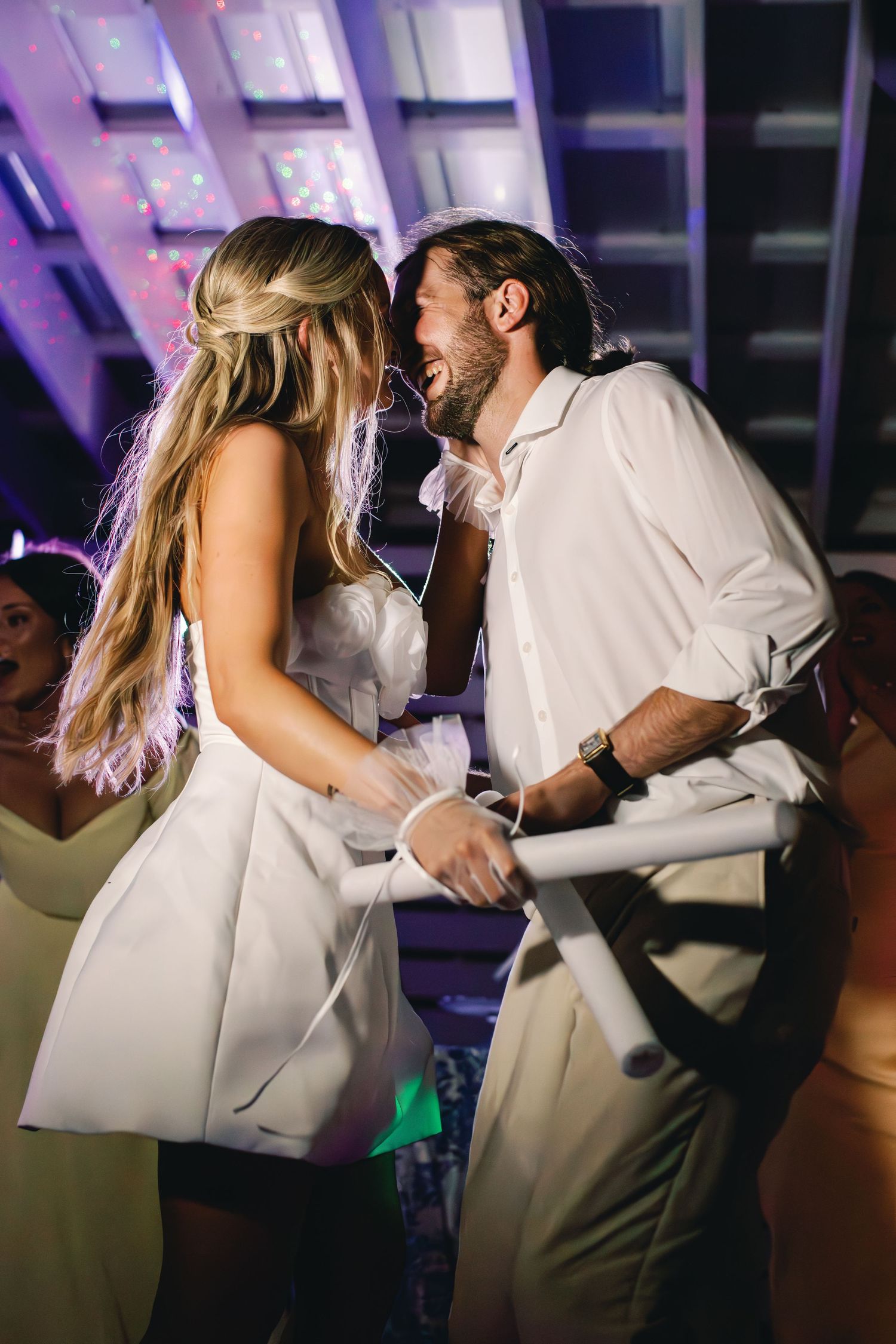 Couple sharing a romantic dance under purple lighting at their wedding reception.