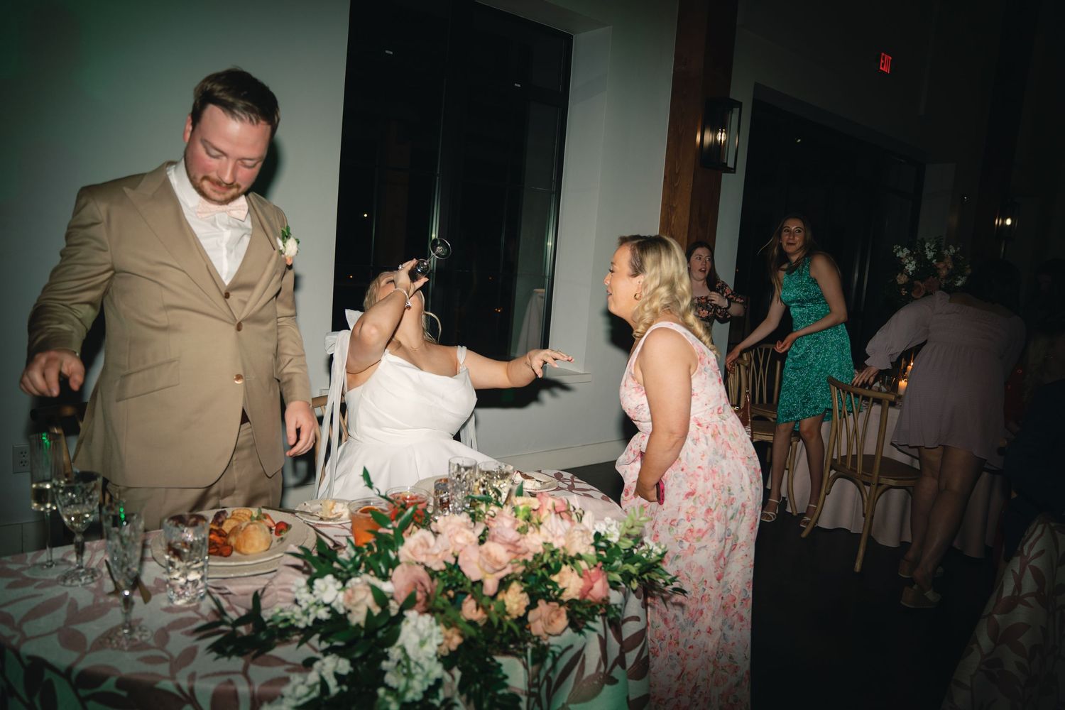 Wedding reception venue with pink floral centerpieces and elegant table settings.