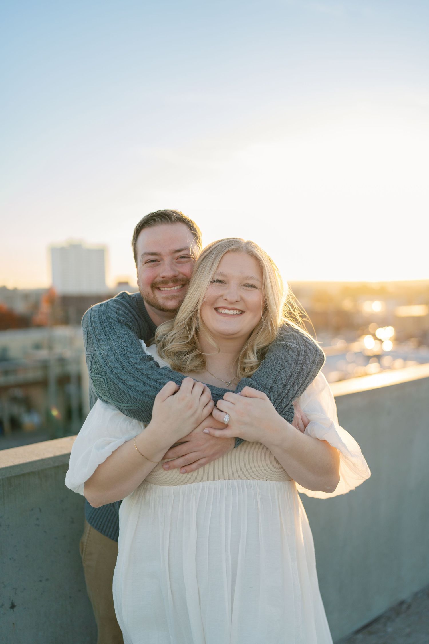 Joyful couple embracing on rooftop during sunset.