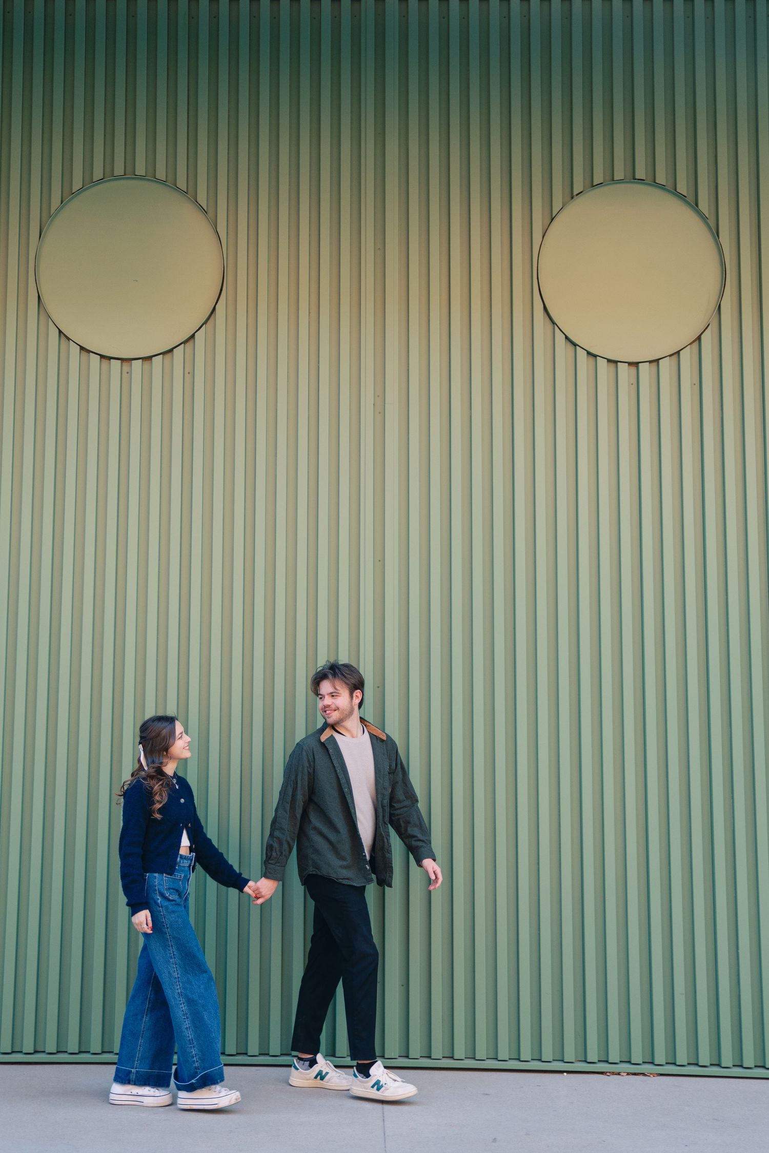 Playful sequence against green corrugated wall showing couple's interaction.