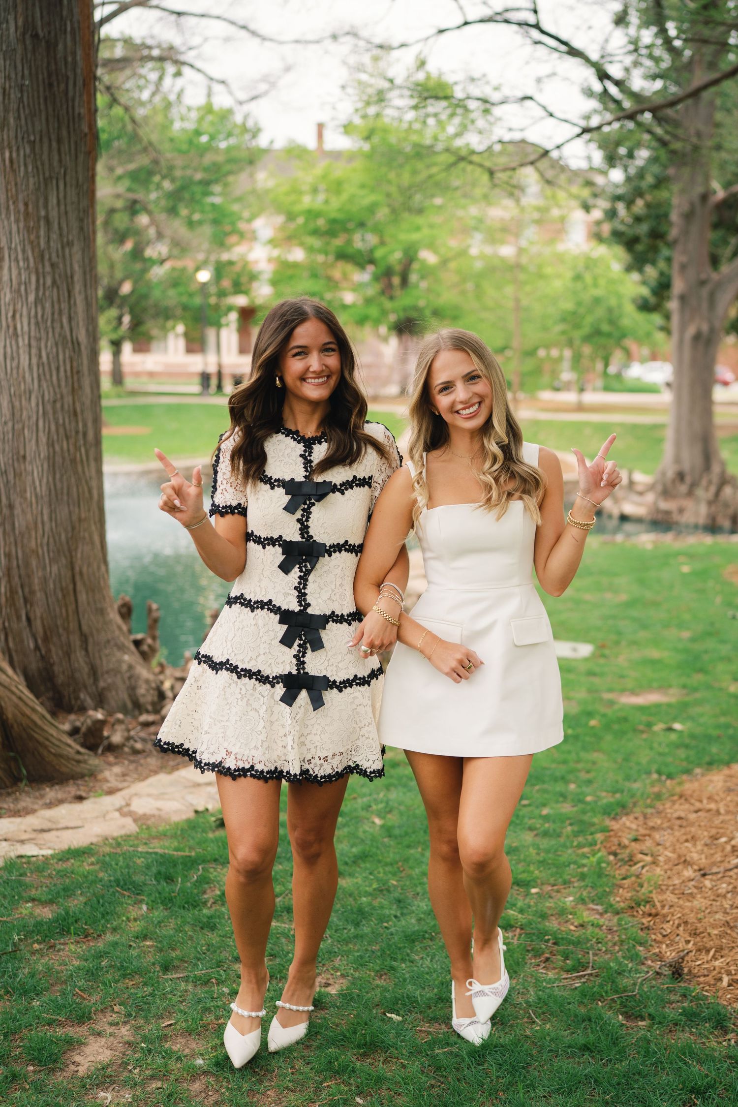 Two friends in coordinating black and white dresses pose together on campus grounds.