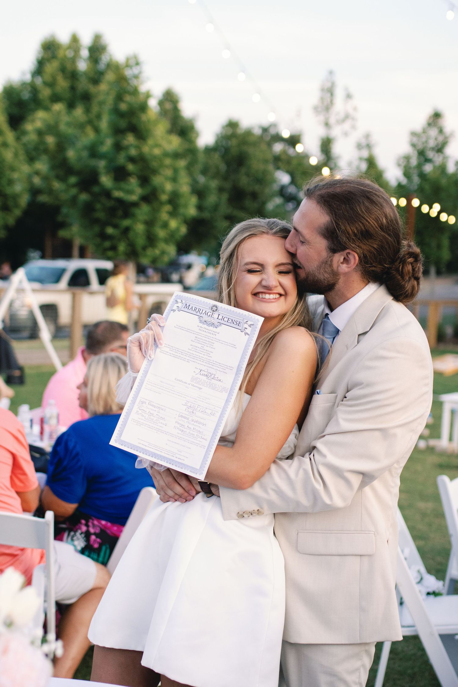 Wedding couple sharing a celebratory moment while holding their marriage certificate.