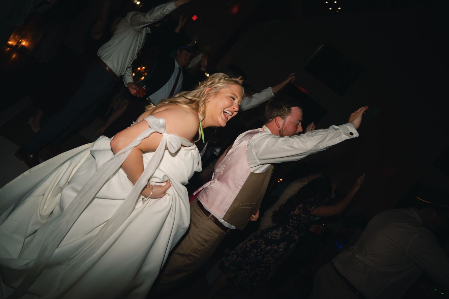 Guests dancing energetically at a wedding reception party.