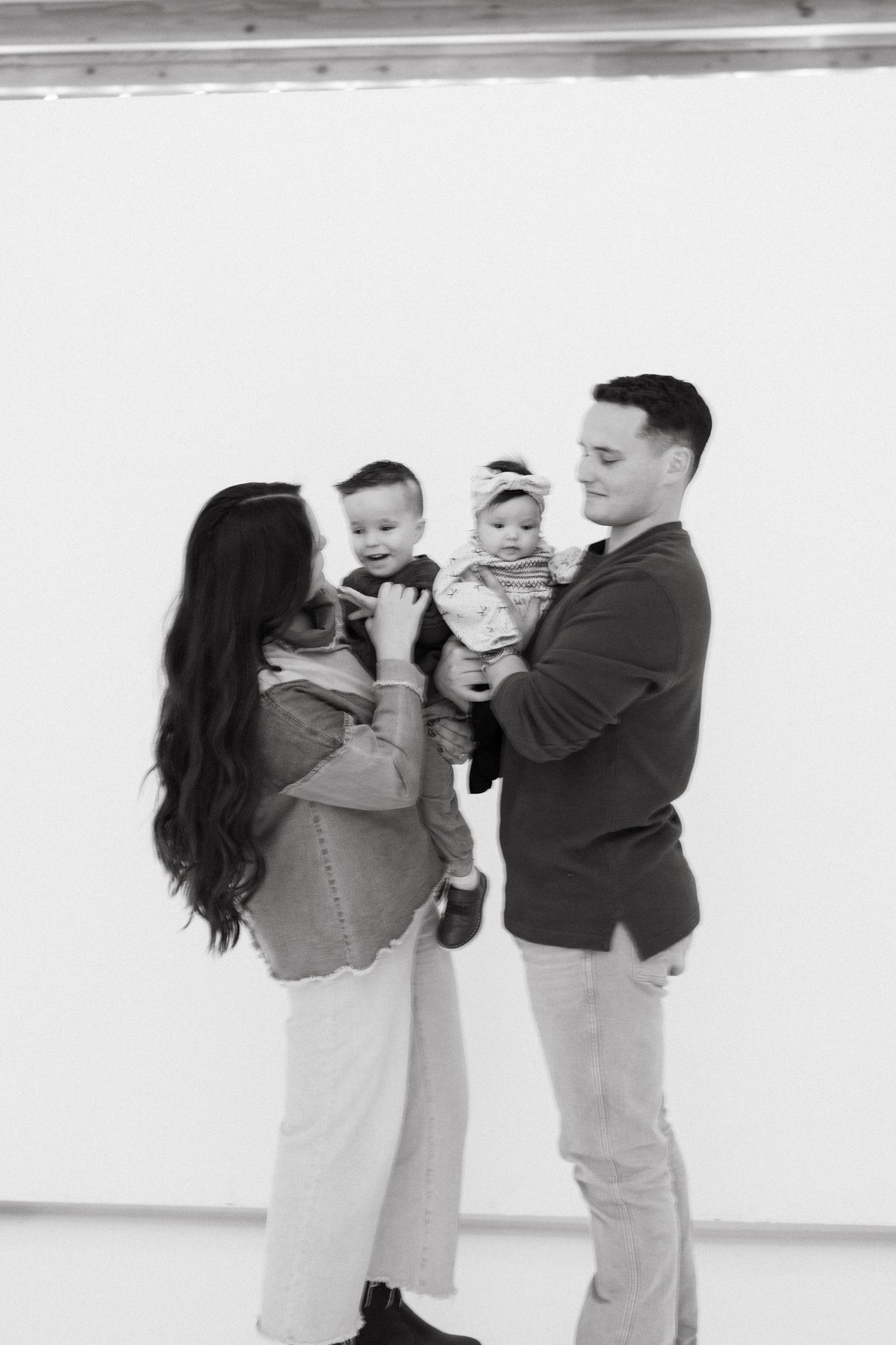 A family of four poses together in a studio setting against a white backdrop, captured in a series of candid moments.