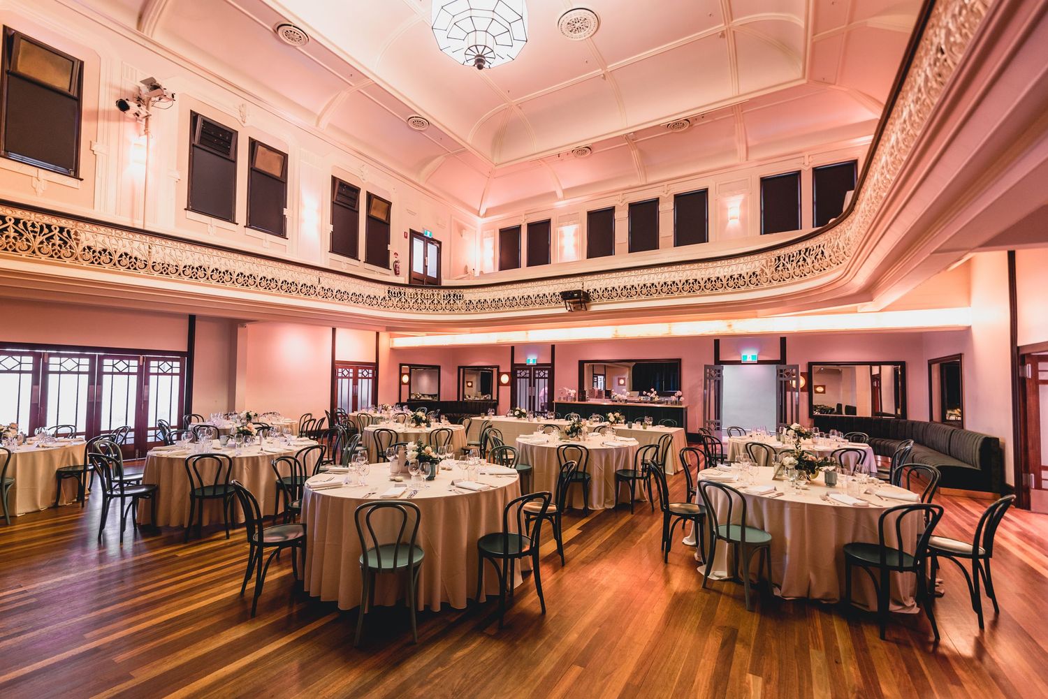 A panoramic view of an elegant banquet hall with white tablecloths, ornate ceiling details and warm lighting.