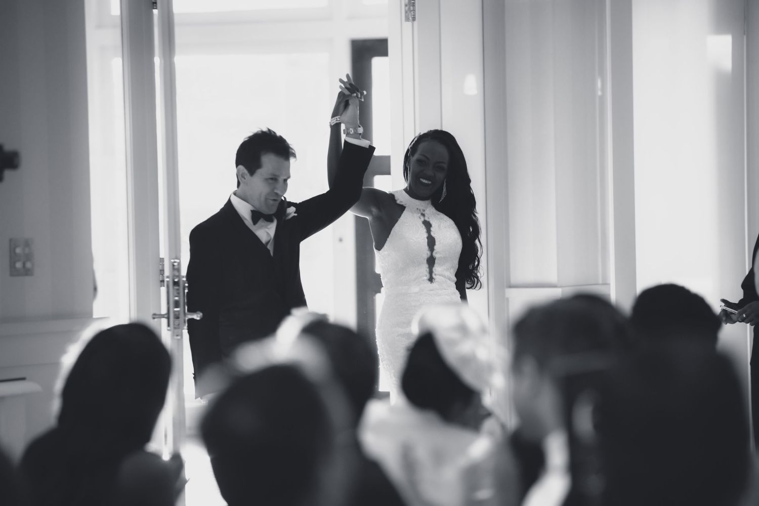 A black and white photo showing a wedding party walking down a bright hallway.