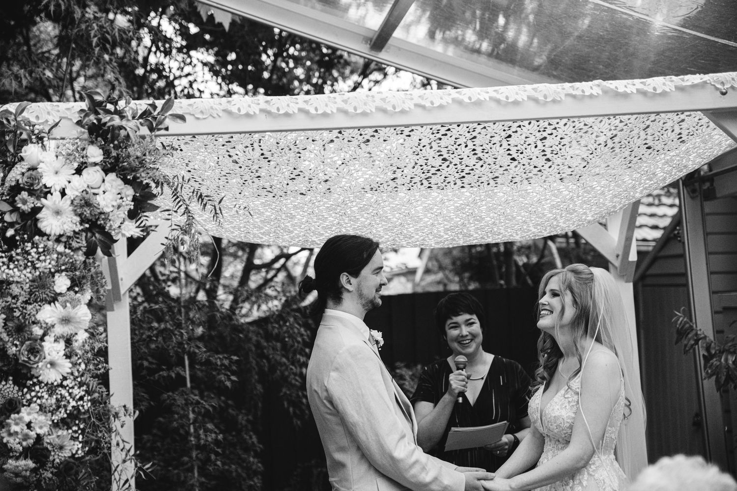 A collection of black and white wedding photos showing couples embracing under outdoor pergolas and garden settings.