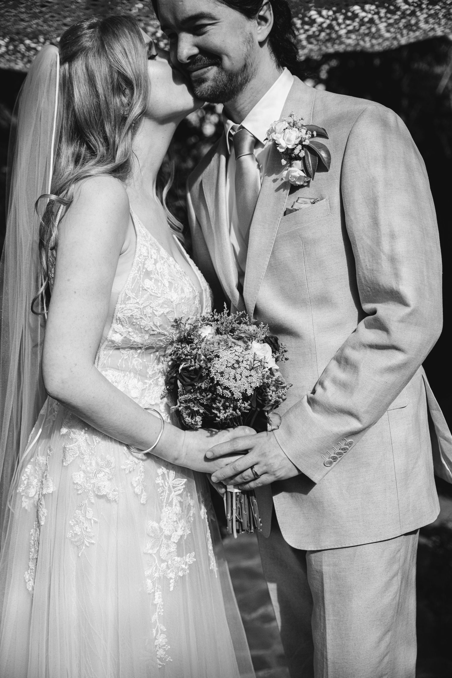 Black and white wedding portraits showing tender moments between newlyweds with delicate bouquet details.